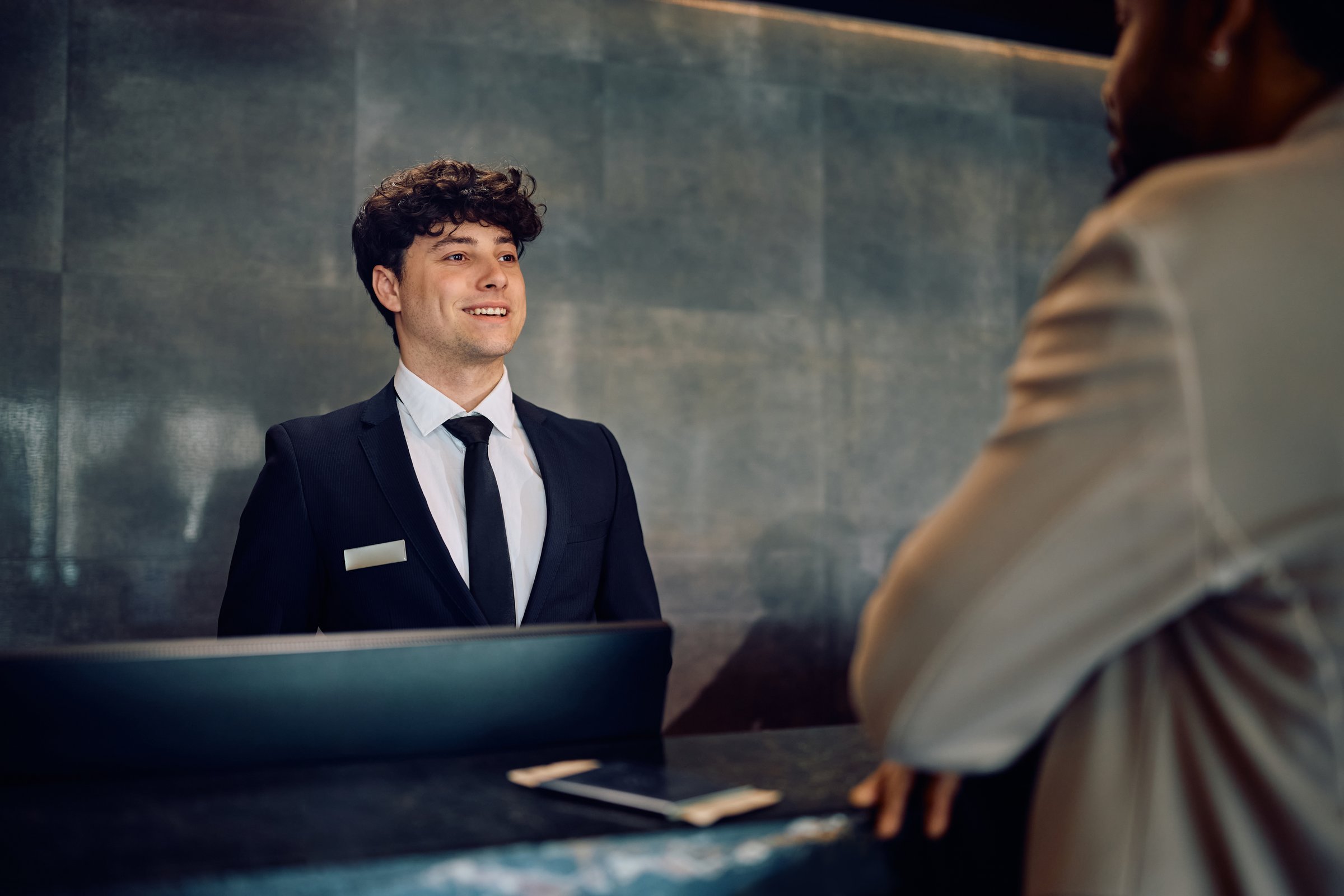Happy concierge talking to African American man who is checking in at the hotel.