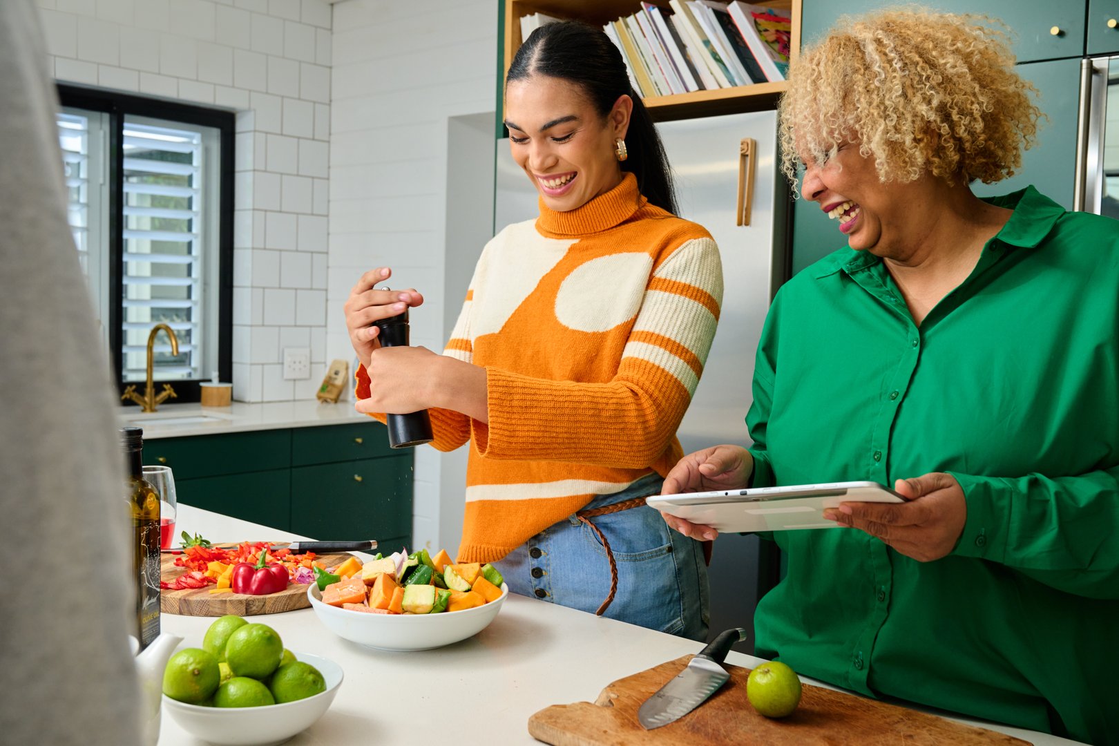 Smiling friends preparing food and looking at tablet in kitchen