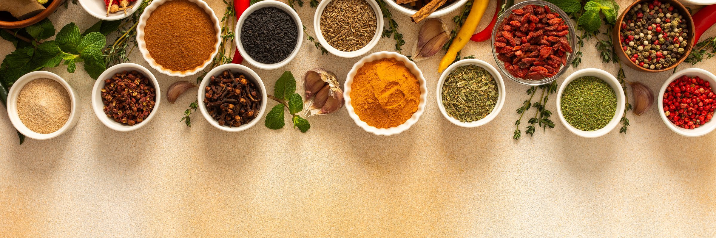 Variety of vibrant spices and dried herbs arranged on a beige backdrop, essential for culinary seasoning and enriching dishes with aromatic, banner