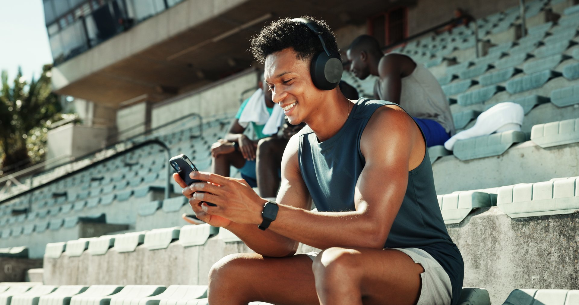 Athlete, headphones and phone with man in stadium for running performance, fitness stats and online training plan. Smile, workout metrics and exercise schedule with person for competition results