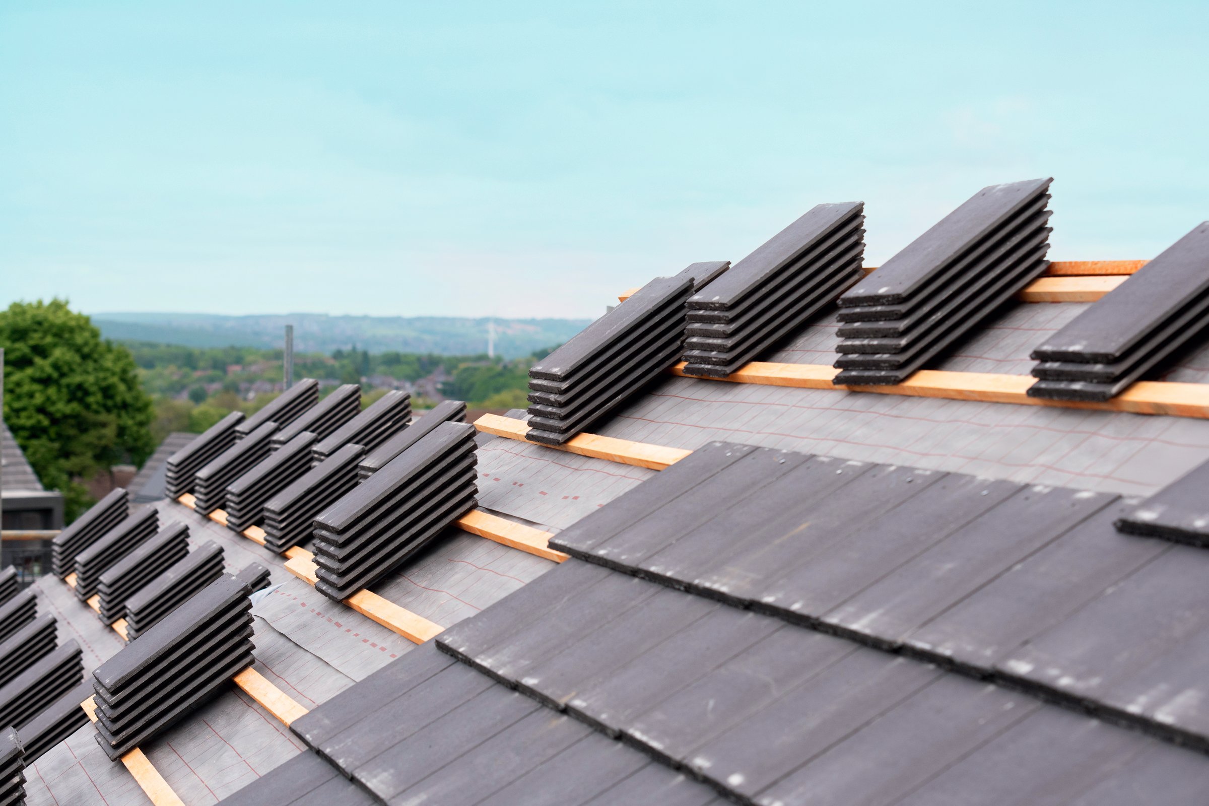 Roof tiles stacked and ready for installation on a residential building during overcast weather conditions