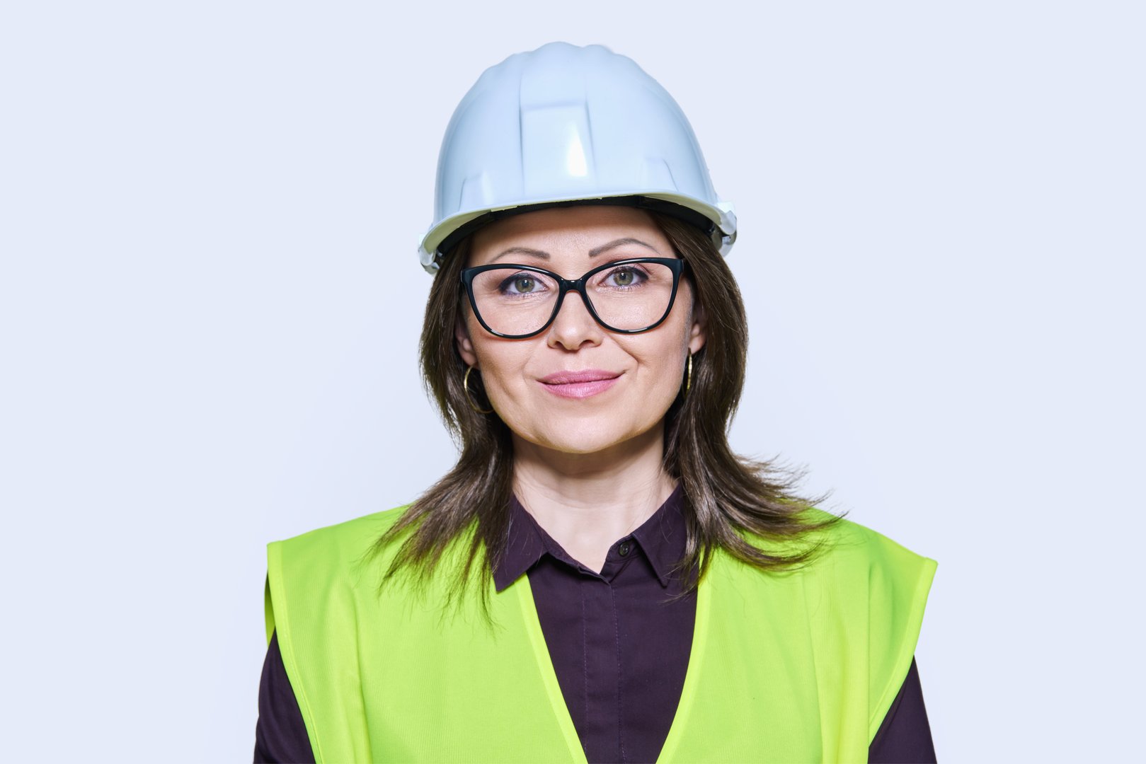 Headshot portrait of female industrial construction worker in hardhat vest looking at camera, white studio background. Logistics construction industry management architecture engineering staff concept