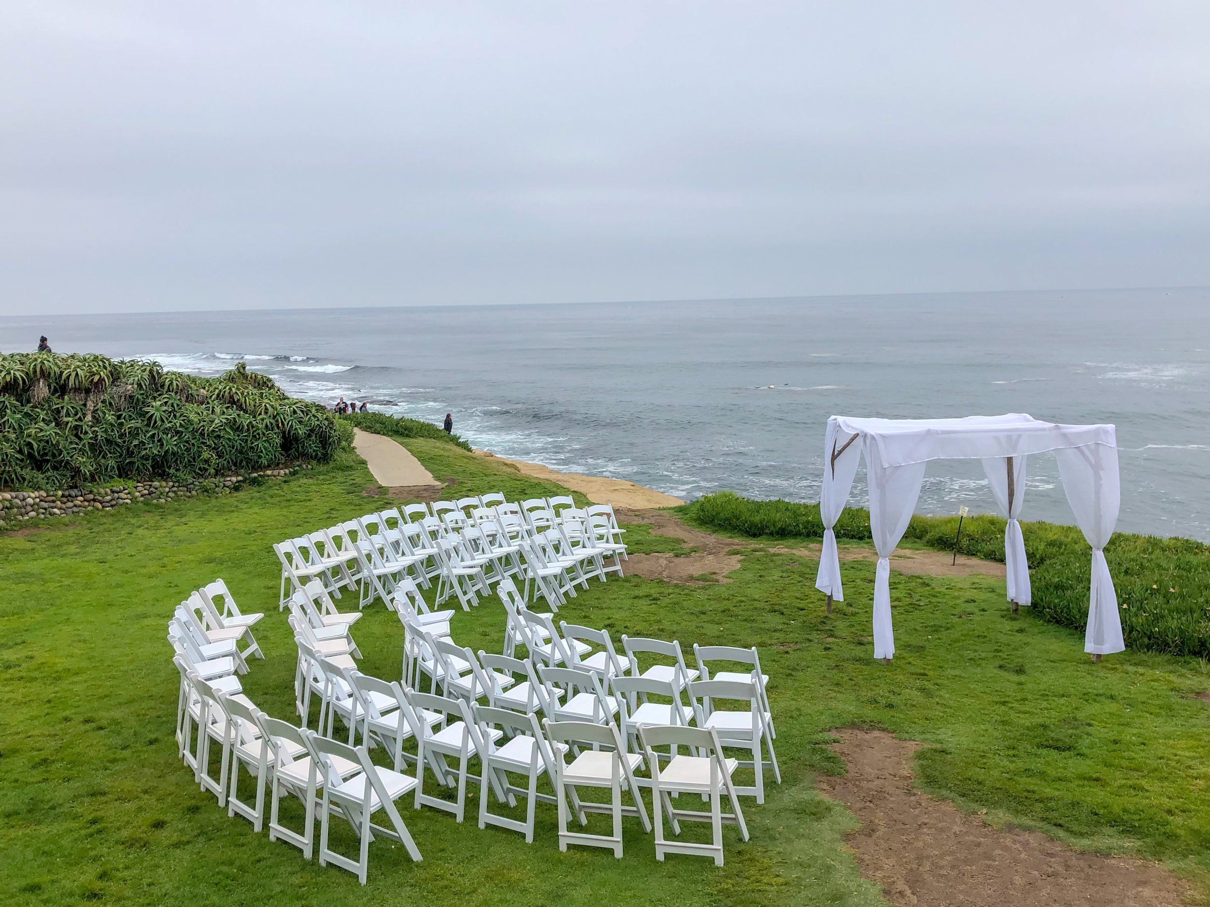 Wedding ceremony setting with white chairs and arch in the garden in front of the ocean, wedding concept, La Jolla, California, USA