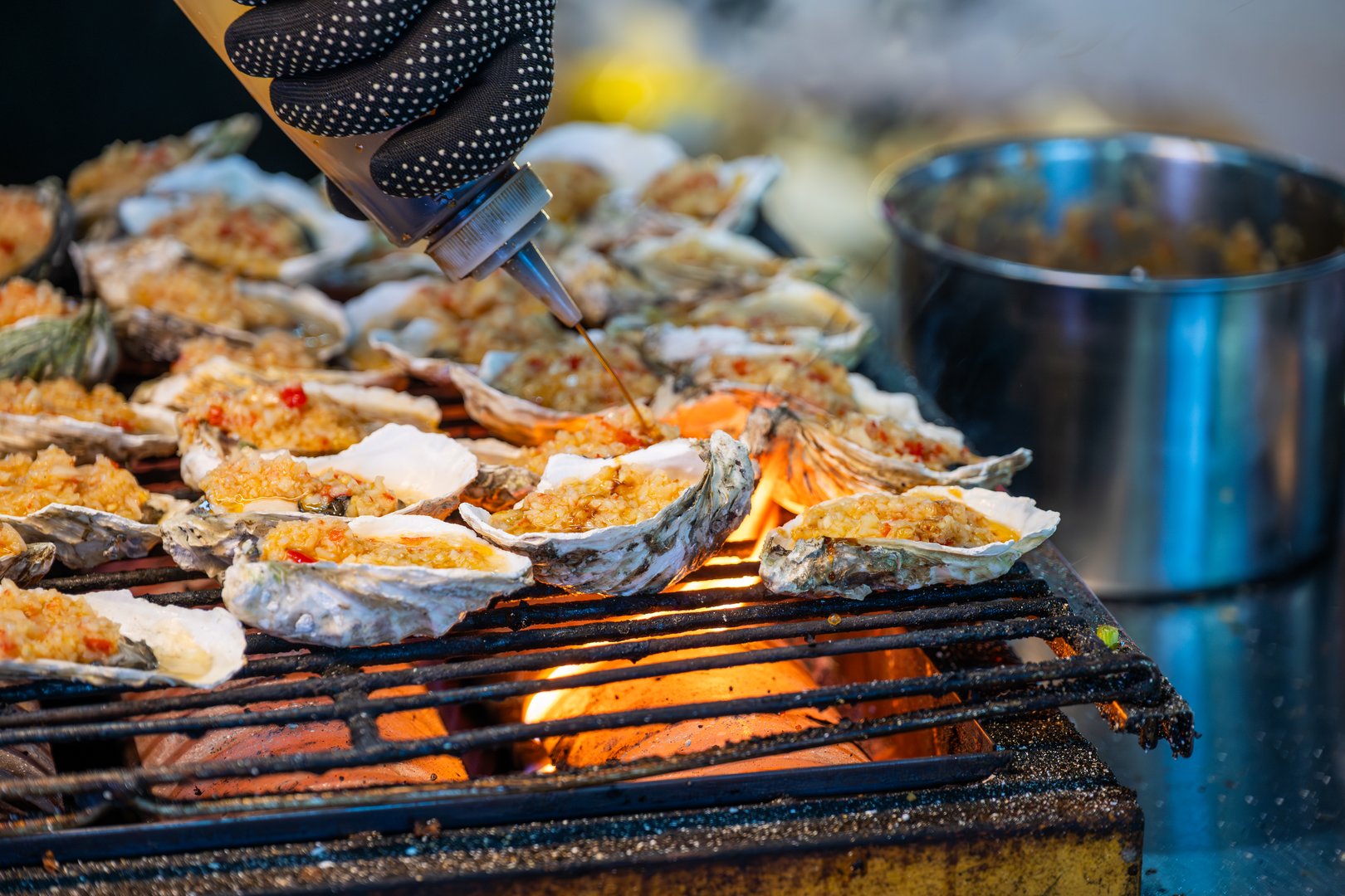 A local cook prepares fresh oysters on a bustling street in Chengdu, Sichuan. These oysters are placed on a grill, perfectly heating over bright flames. The cook skillfully adds a spicy topping, enhancing the flavors and enticing customers nearby. The atmosphere is lively with street vendors and curious onlookers enjoying the delicious aroma. This traditional dish showcases the vibrant culinary culture of Chengdu, where seafood is a popular choice among locals and tourists alike.