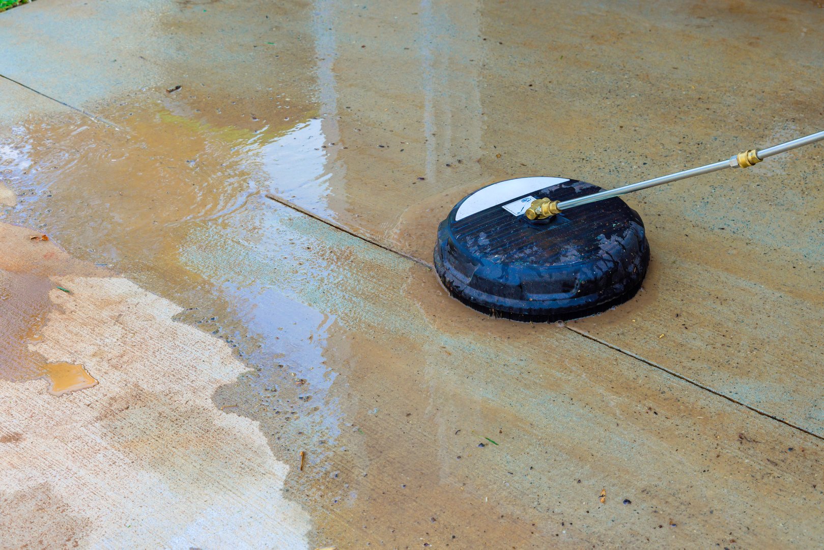 Pressure washer is being used to clean concrete surface, removing dirt, grime effectively outdoors.