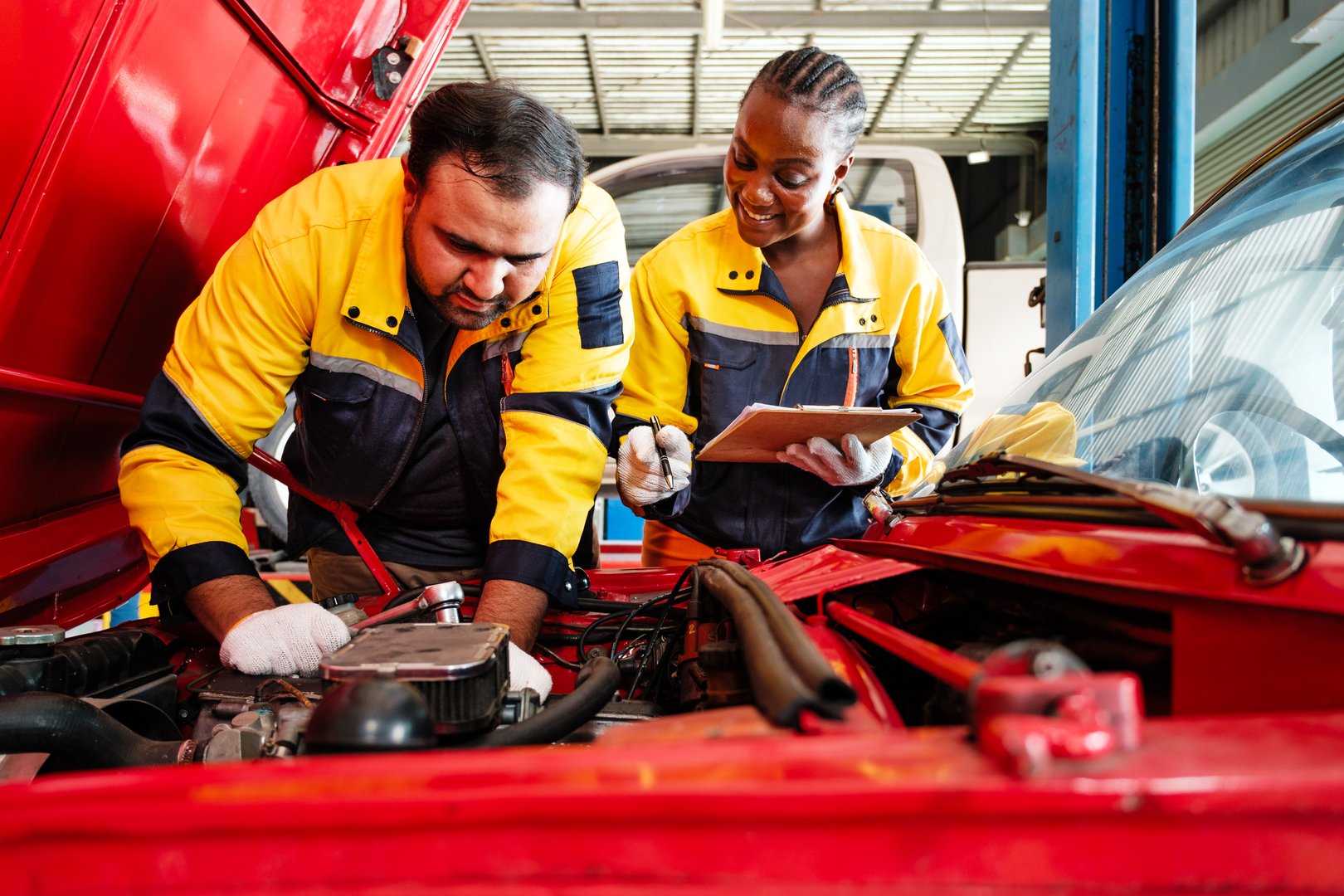 Diverse professional auto repair team working together on a car engine in a garage. Highlights teamwork, inclusion, expertise, and reliable automotive maintenance in a skilled service environment.