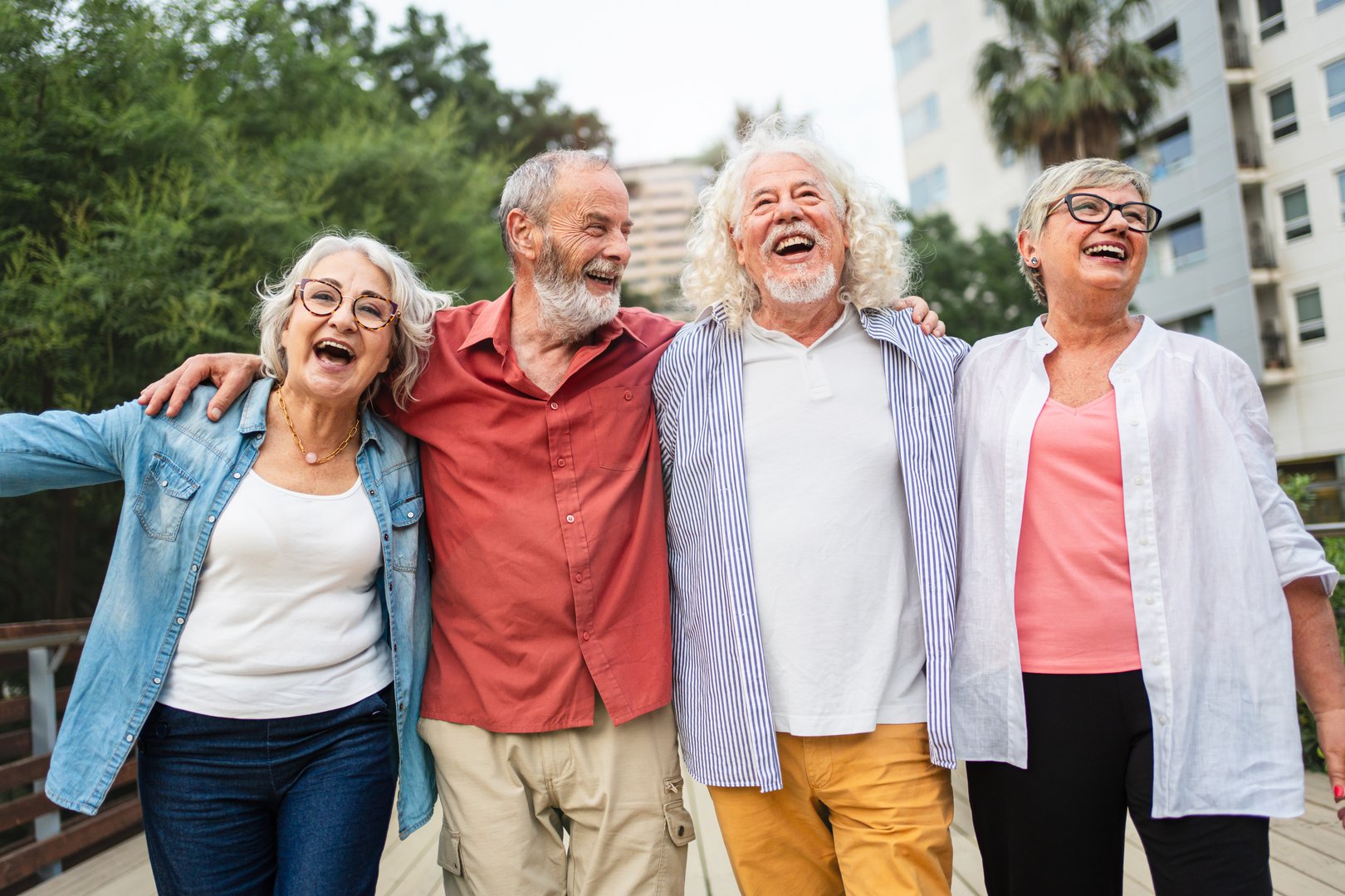 Group of senior friends embracing together laughing and having fun hugging happy in the urban city park