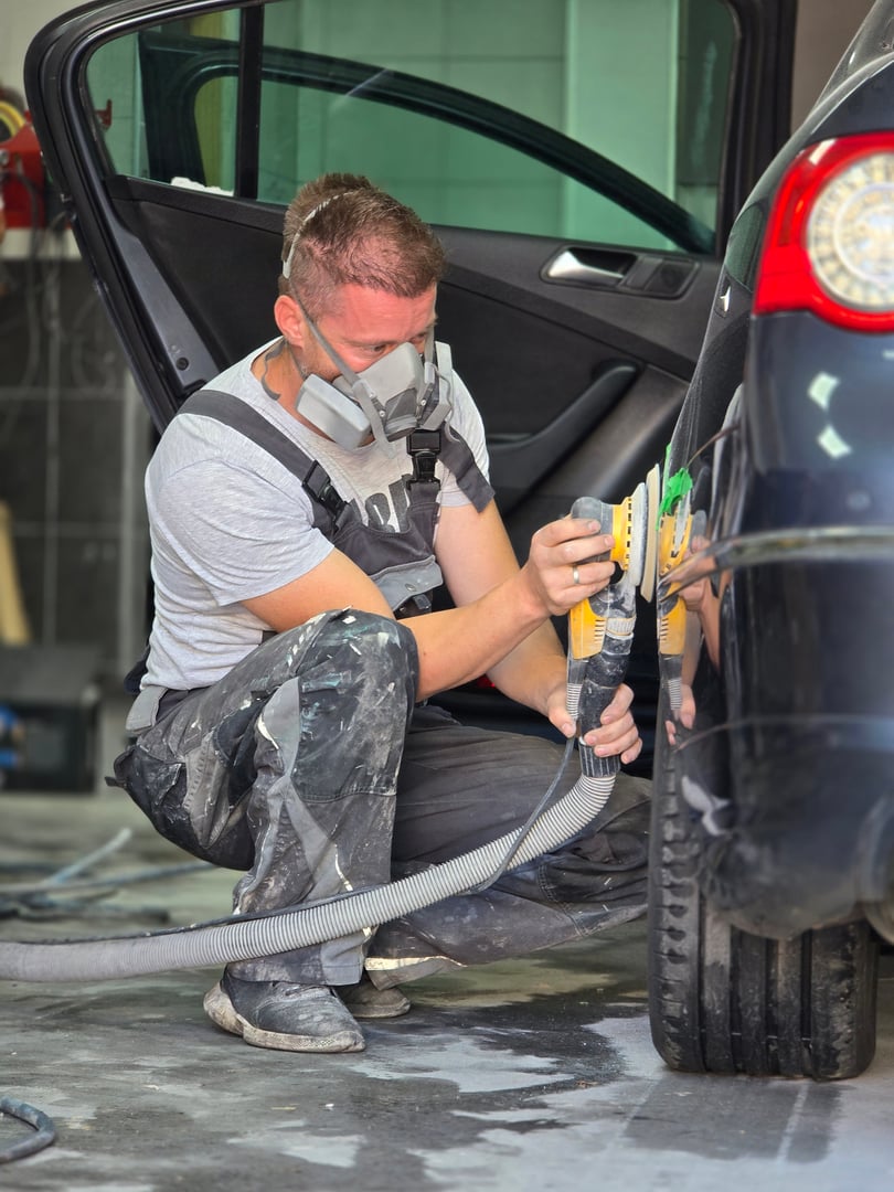 A skilled auto painter meticulously polishing a car to prepare it for painting, showcasing precision and craftsmanship in the workshop
