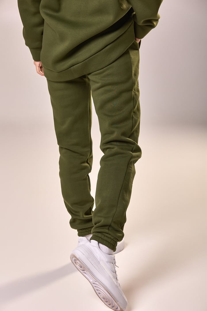 Olive green tracksuit and casual sneakers on male model showcasing modern sportswear concept