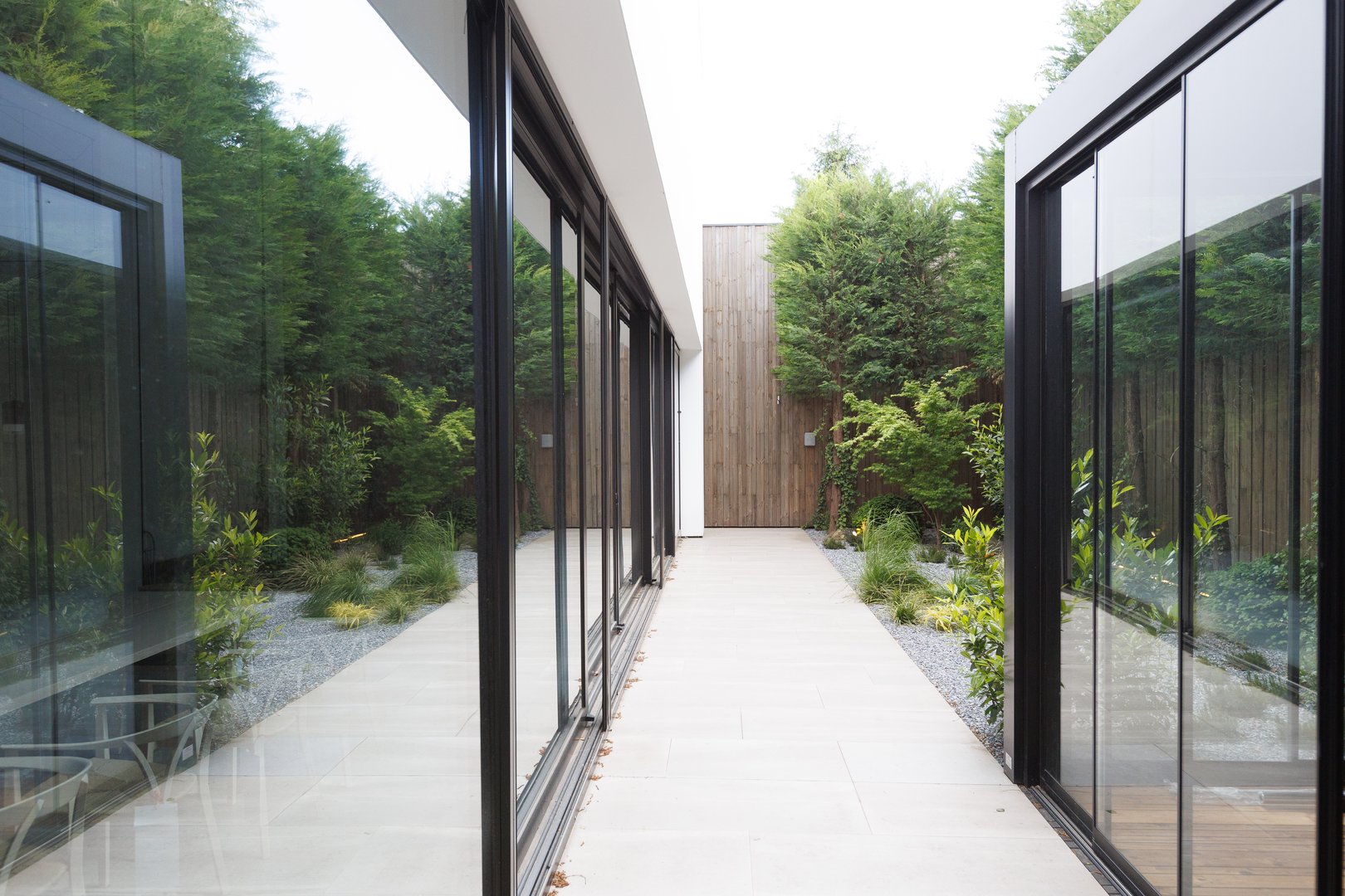 An extensive and elongated hallway running between two separate buildings, adorned with numerous large windows that invite ample sunlight in