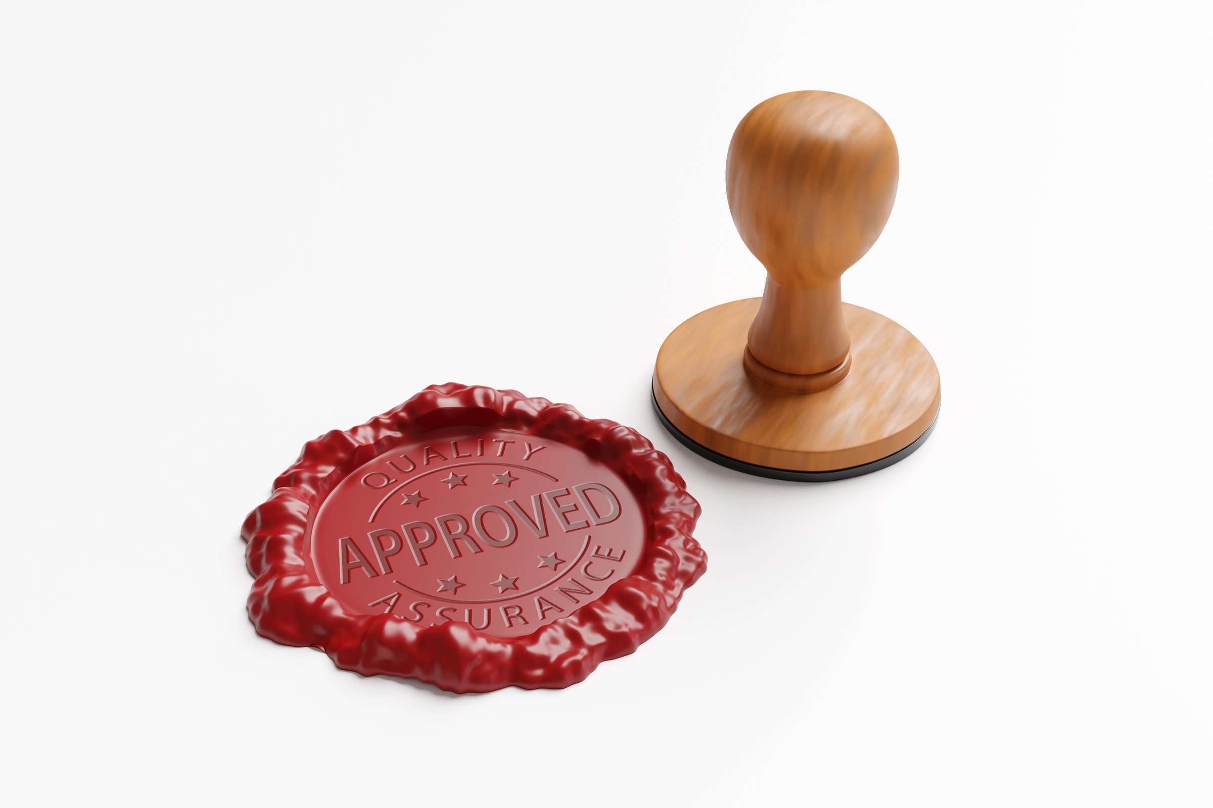 Red waxy seal mark showing the words QUALITY ASSURANCE APPROVED next to a wooden stamp. Illustration of the concept of quality control and the highest product standards