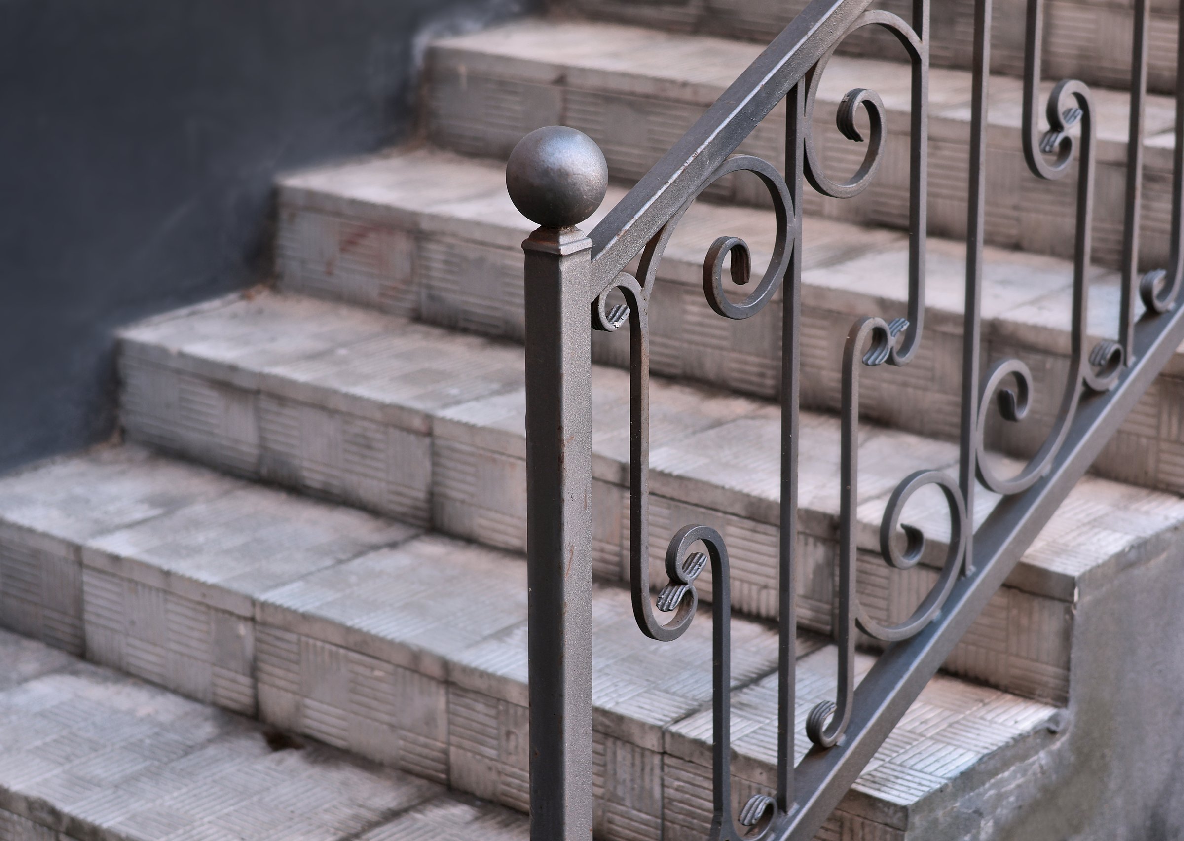 Wrought iron railing near stairs on tile porch of private home.