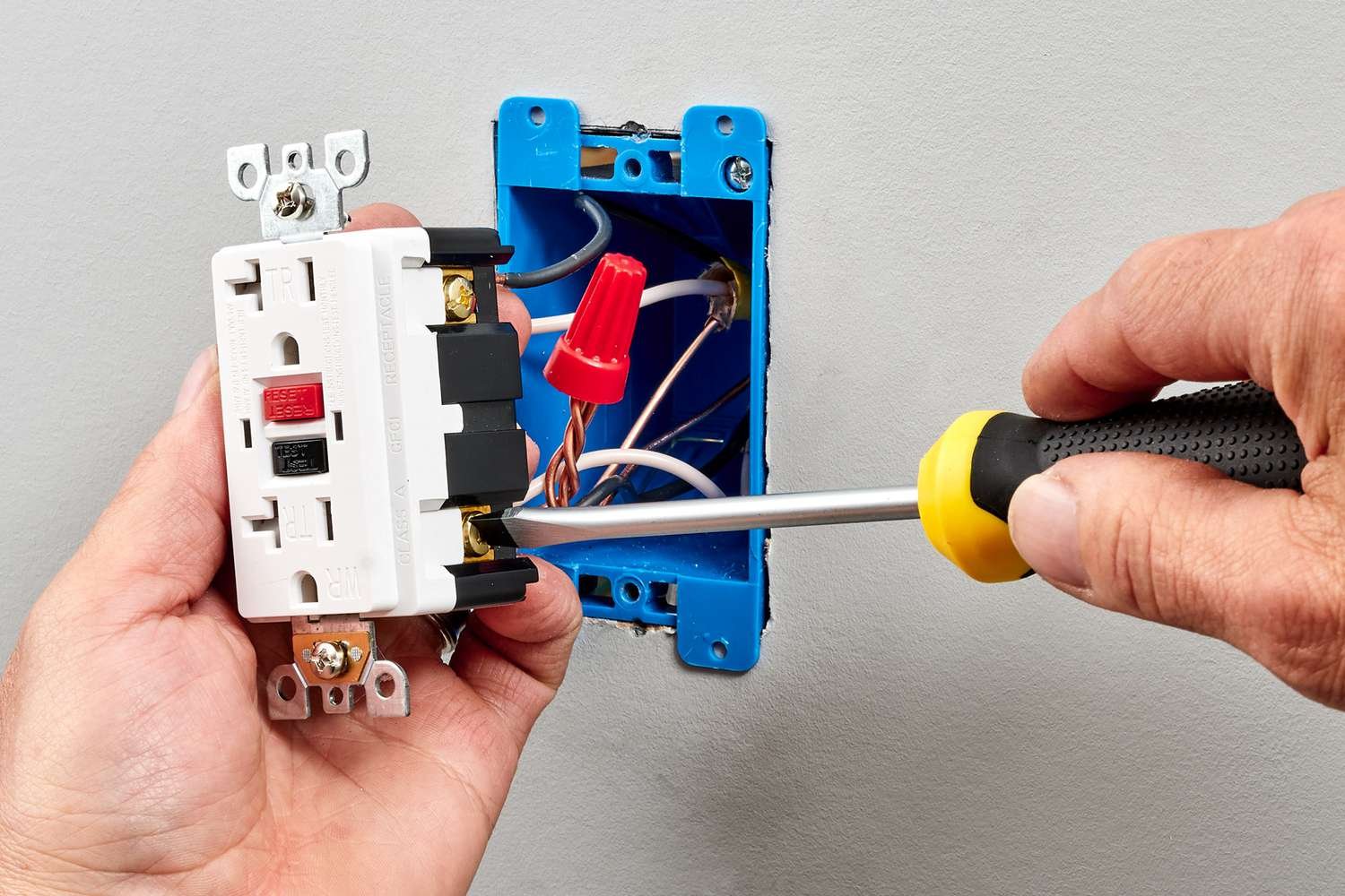 Professional electrician working on a home electrical system, he is installing a wall socket