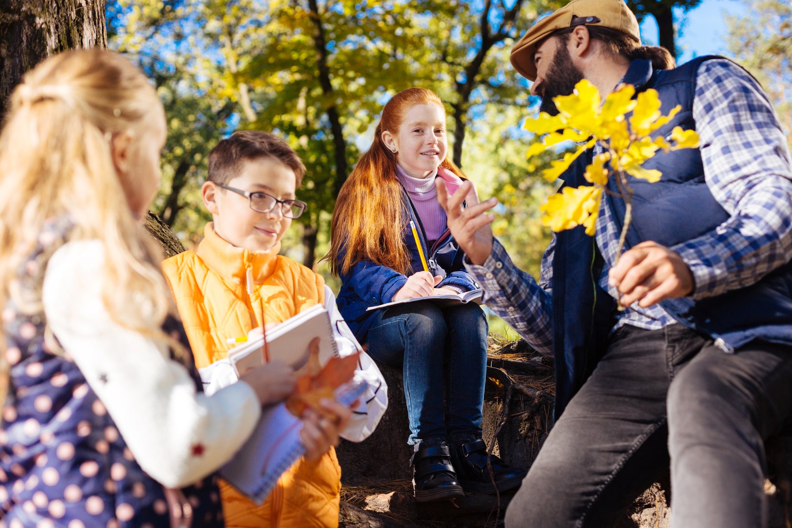 On the excursion. Delighted curious children listening to their teacher while being with him in the forest