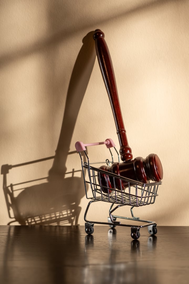 Judge gavel and miniature shopping cart from a supermarket