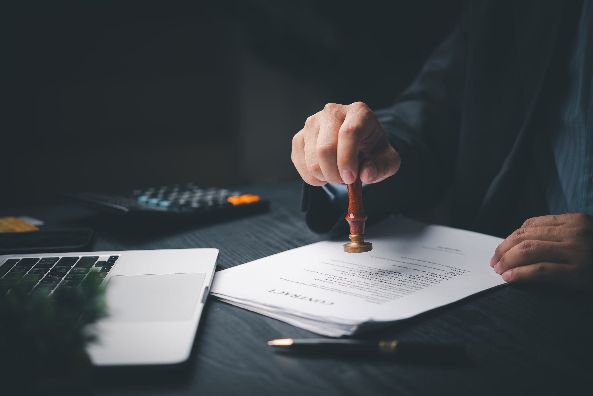 Man Holding Stamp Rubber Document Agreement Office Or Visa Approval Official Legal on desk.