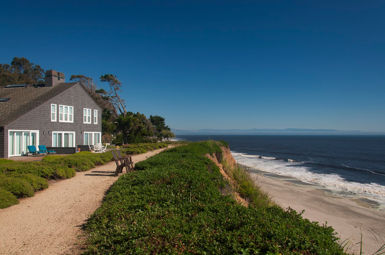 A cliff side home in northern california overlooking the pacific ocean on a sunny day.