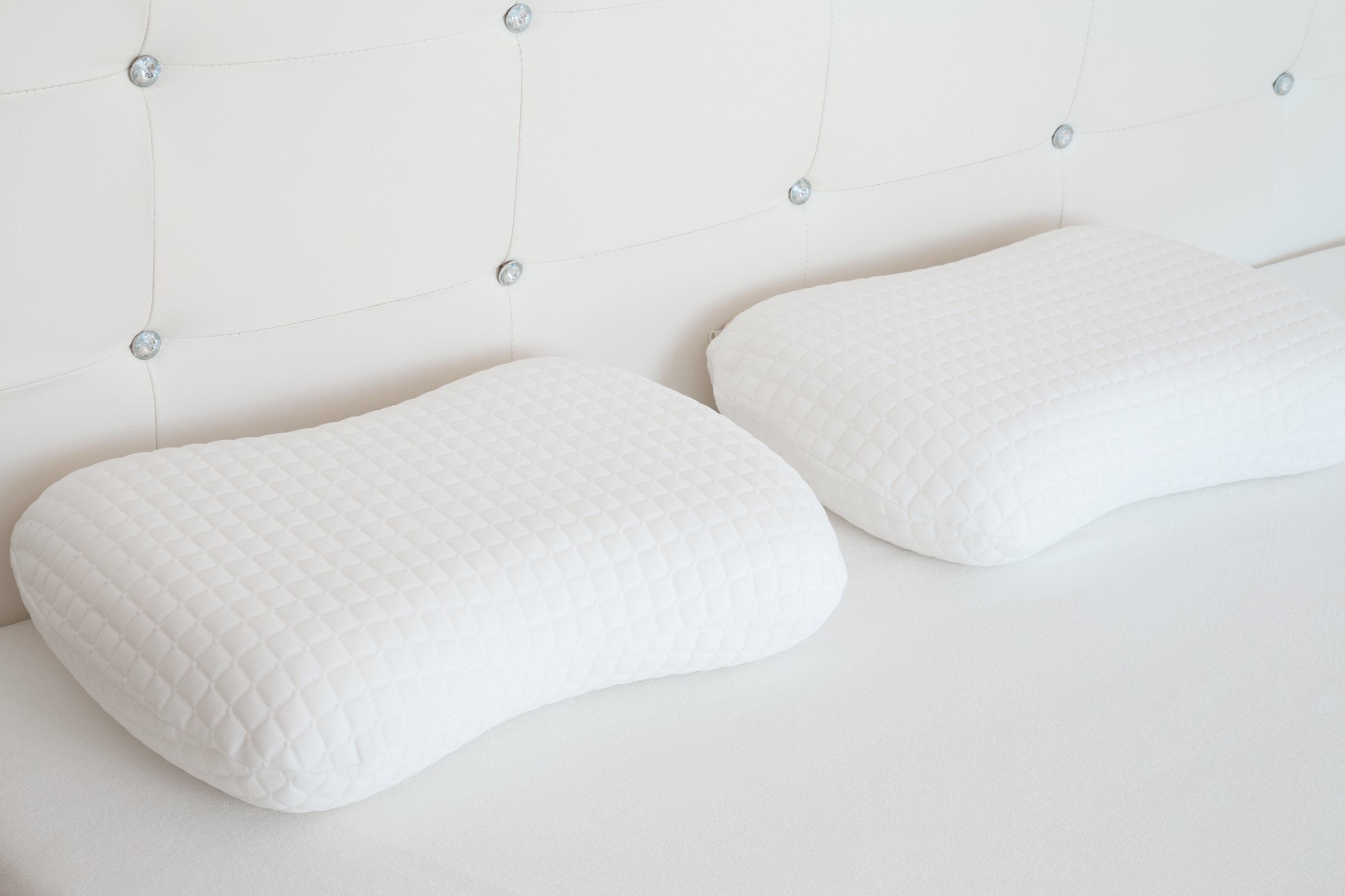 Two white soft memory foam pillows on mattress. Closeup.