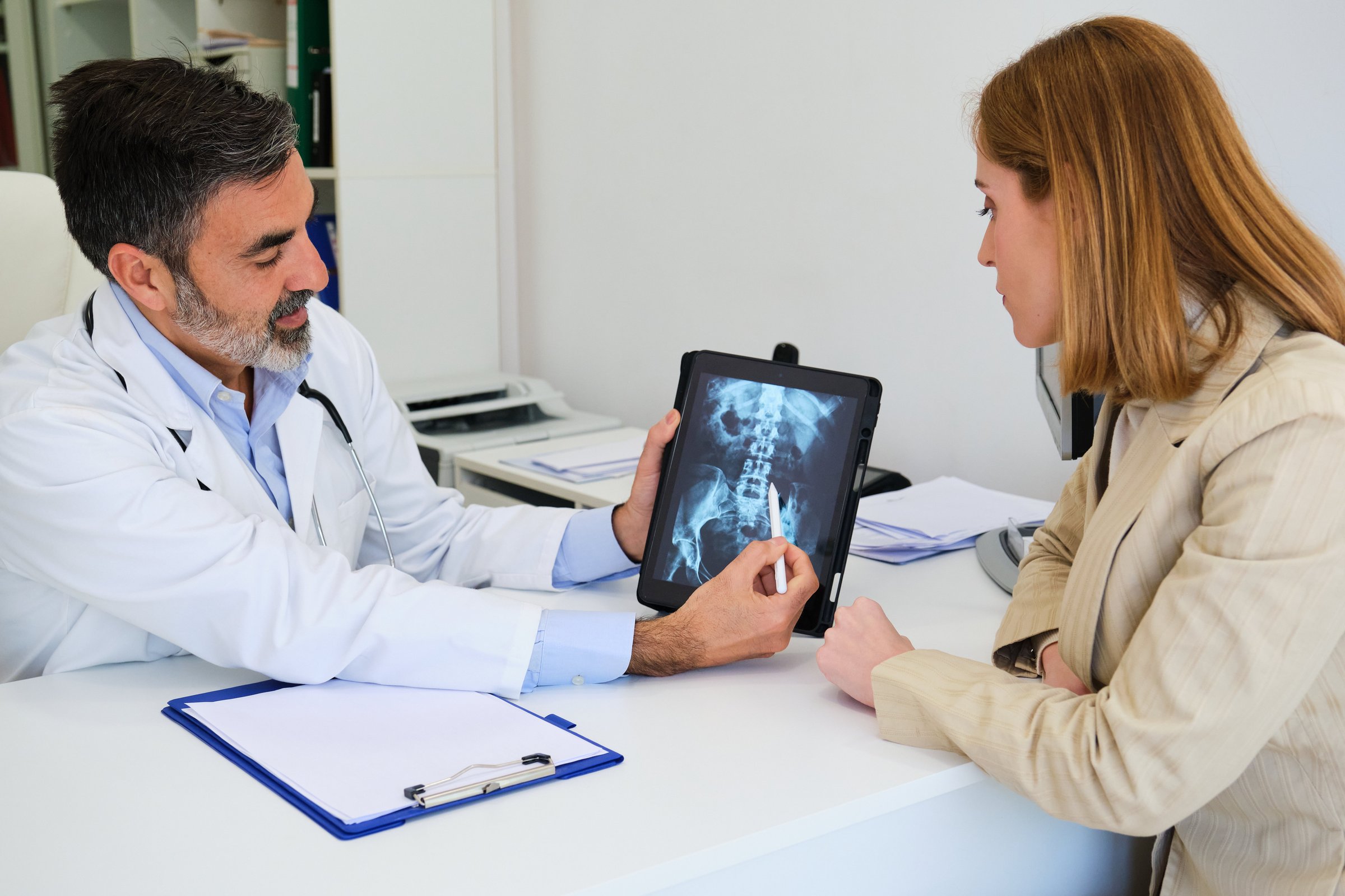 Doctor explaining x-ray to his female patient after surgery for a broken hip. Healthcare and medicine.