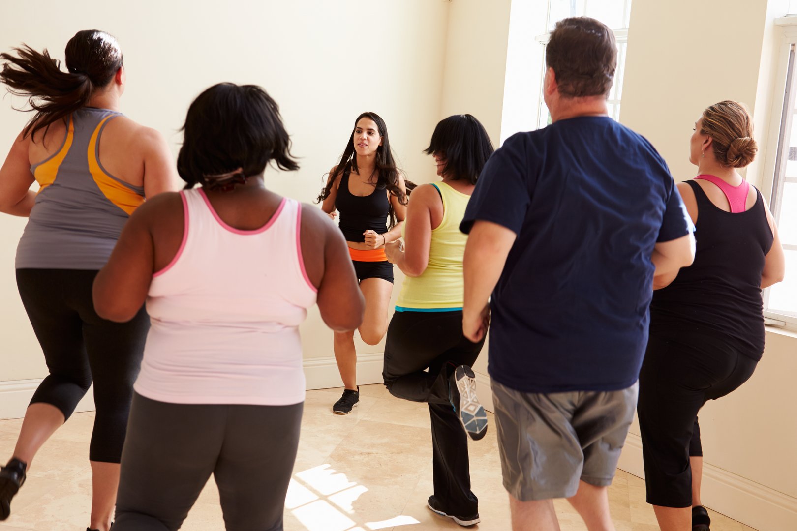 Fitness Instructor In Exercise Class For Overweight People Running On The Spot