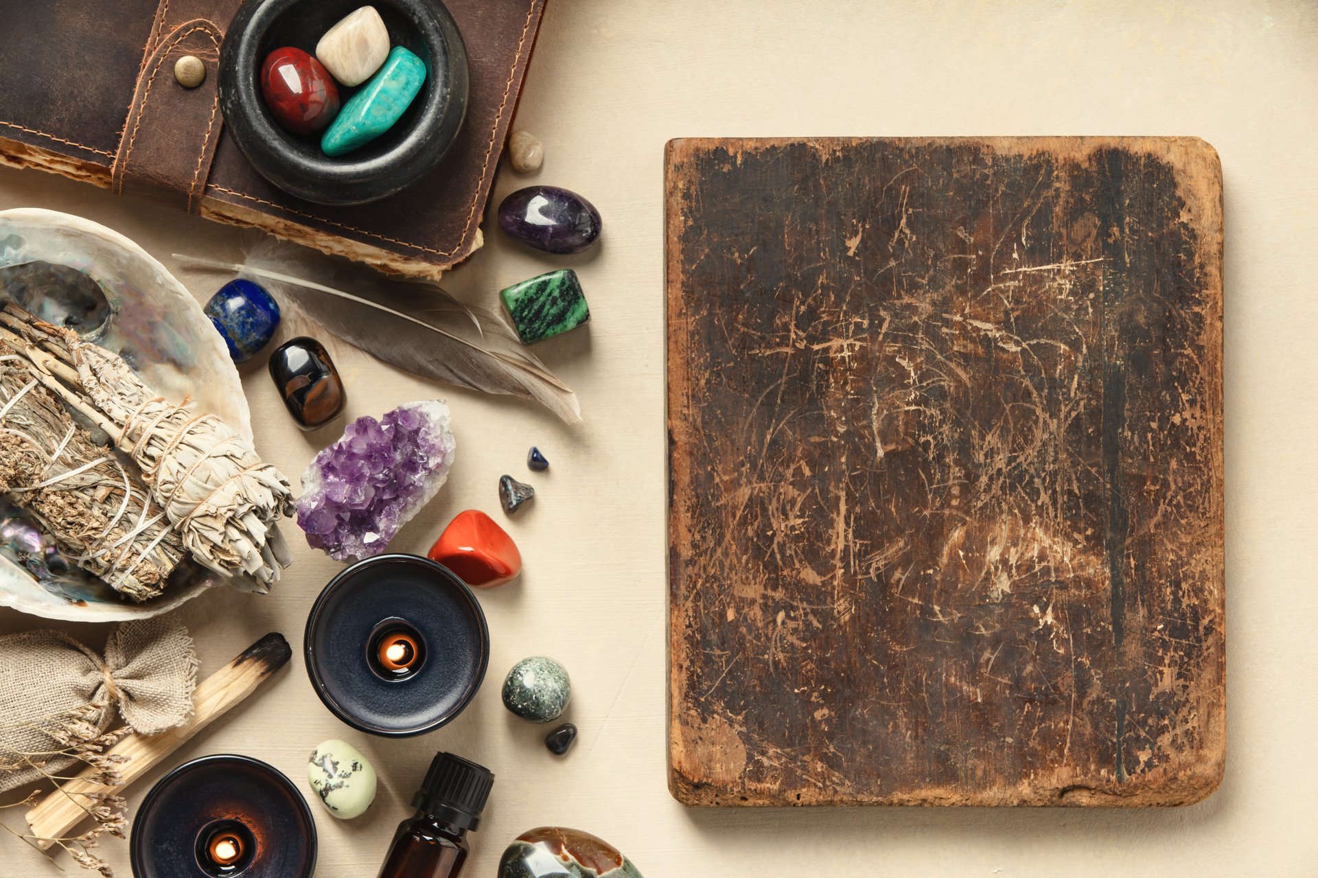 Collection of sage, crystals, feathers, and candles for wellness and spiritual rituals, arranged aesthetically on a textured background.