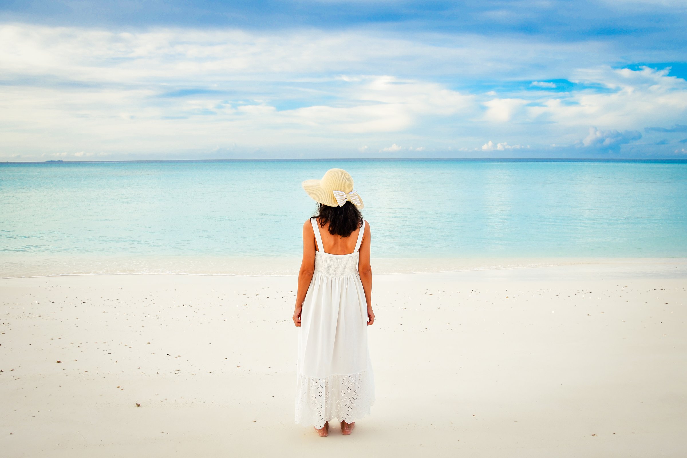 Tropical Maldives beach woman stand in middle enjoy turquoise blue ocean with sunrise view panorama banner. Elegant luxury vacation. Maldives postcard woman tanned back view