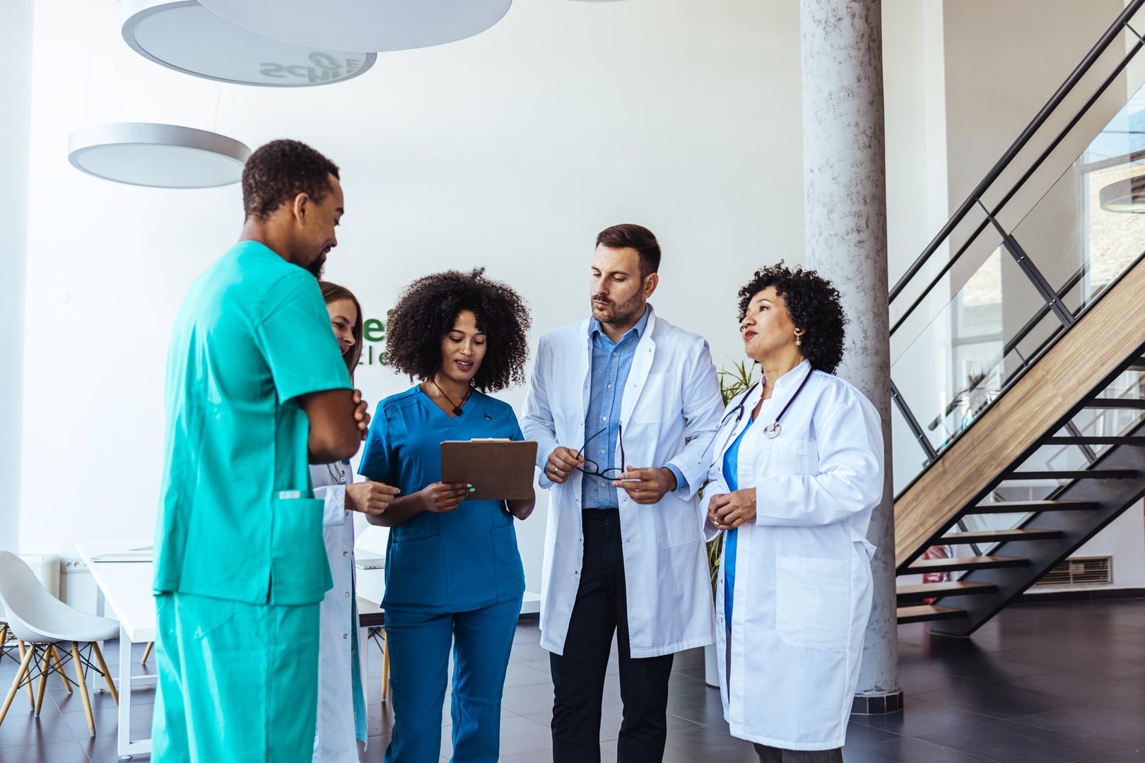 Medical team including doctors and nurses discussing patient cases in a healthcare facility.