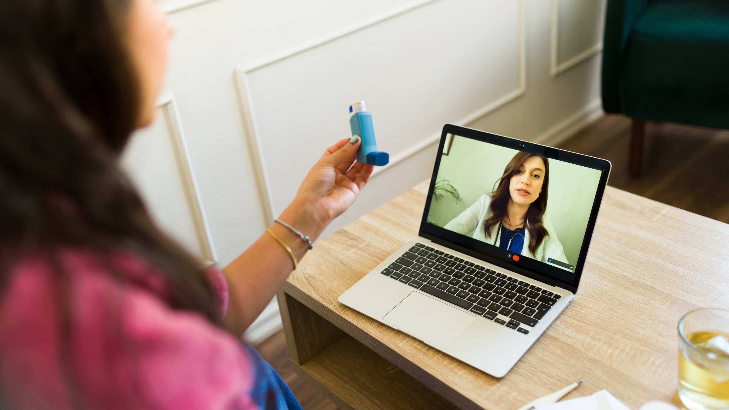 Closeup of a woman conducting an online medical consultation and displaying her inhaler to the doctor