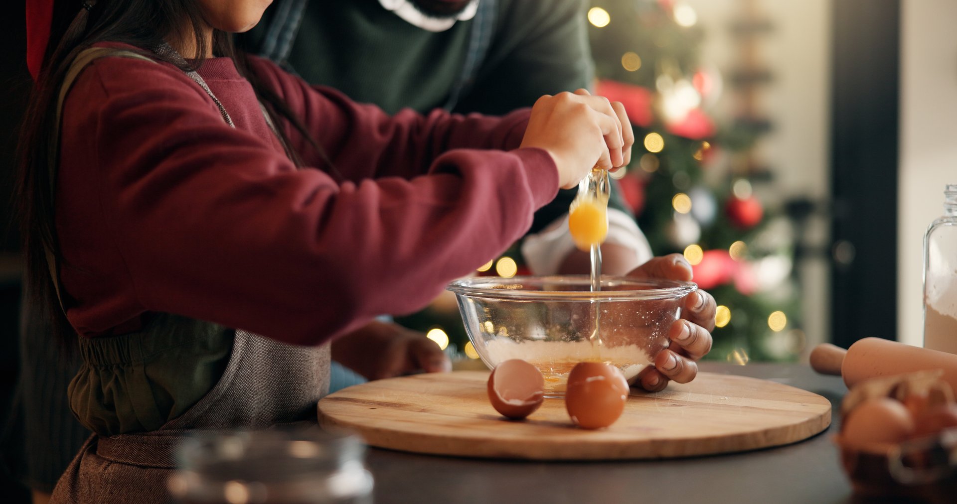 Christmas, eggs and hands of child with parent in kitchen of home for festive tradition or help. Baking, holidays and bowl with family at apartment together for cooking or learning in December season