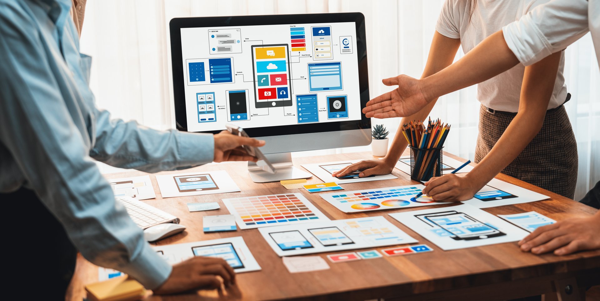 Panorama shot of front-end developer team brainstorming UI and UX designs for mobile app on laptop computer screen. User interface development team planning for user-friendly UI design. Scrutinize
