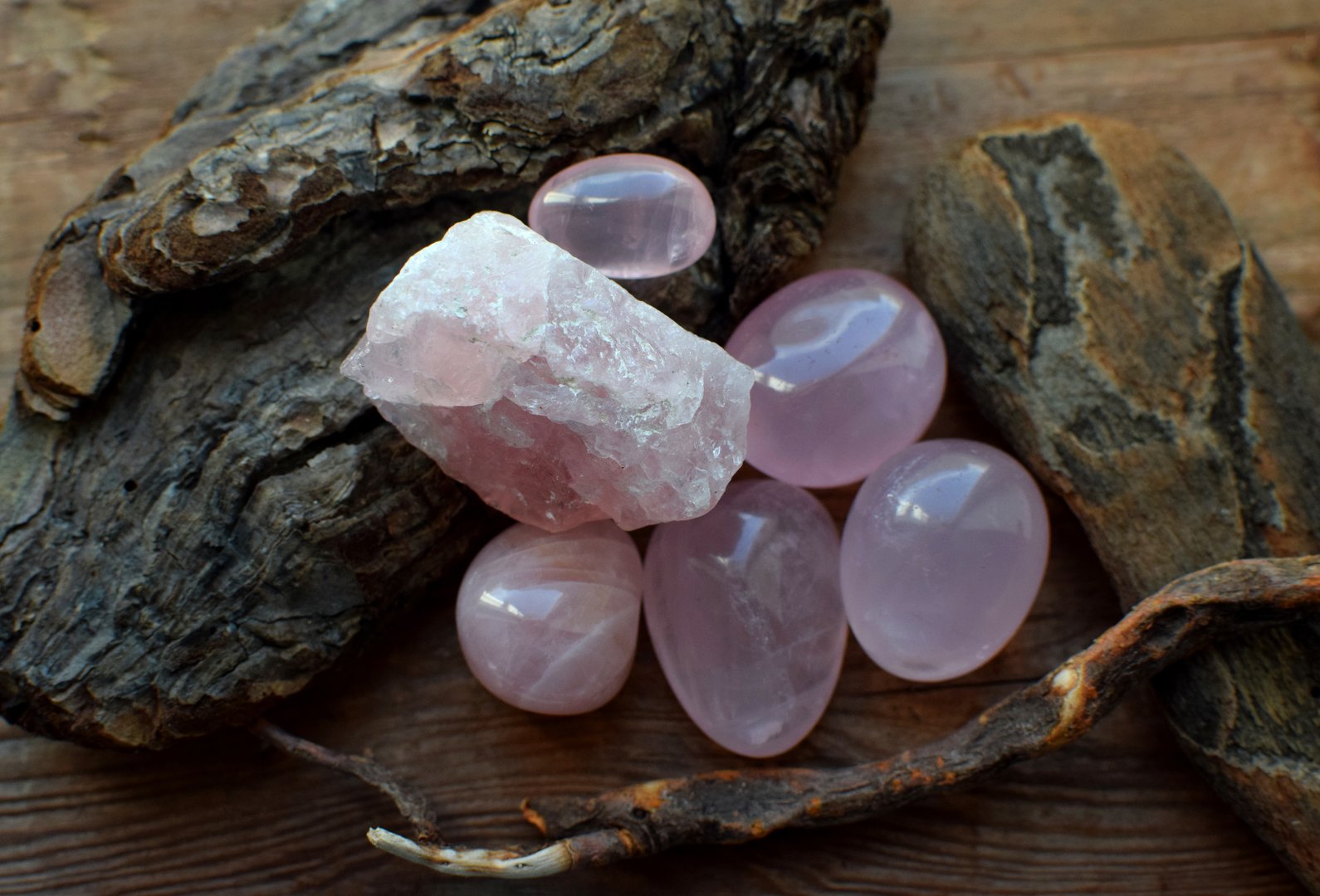 Beautiful stones of natural rose quartz on a wooden background. Healing crystals. Selective focus.