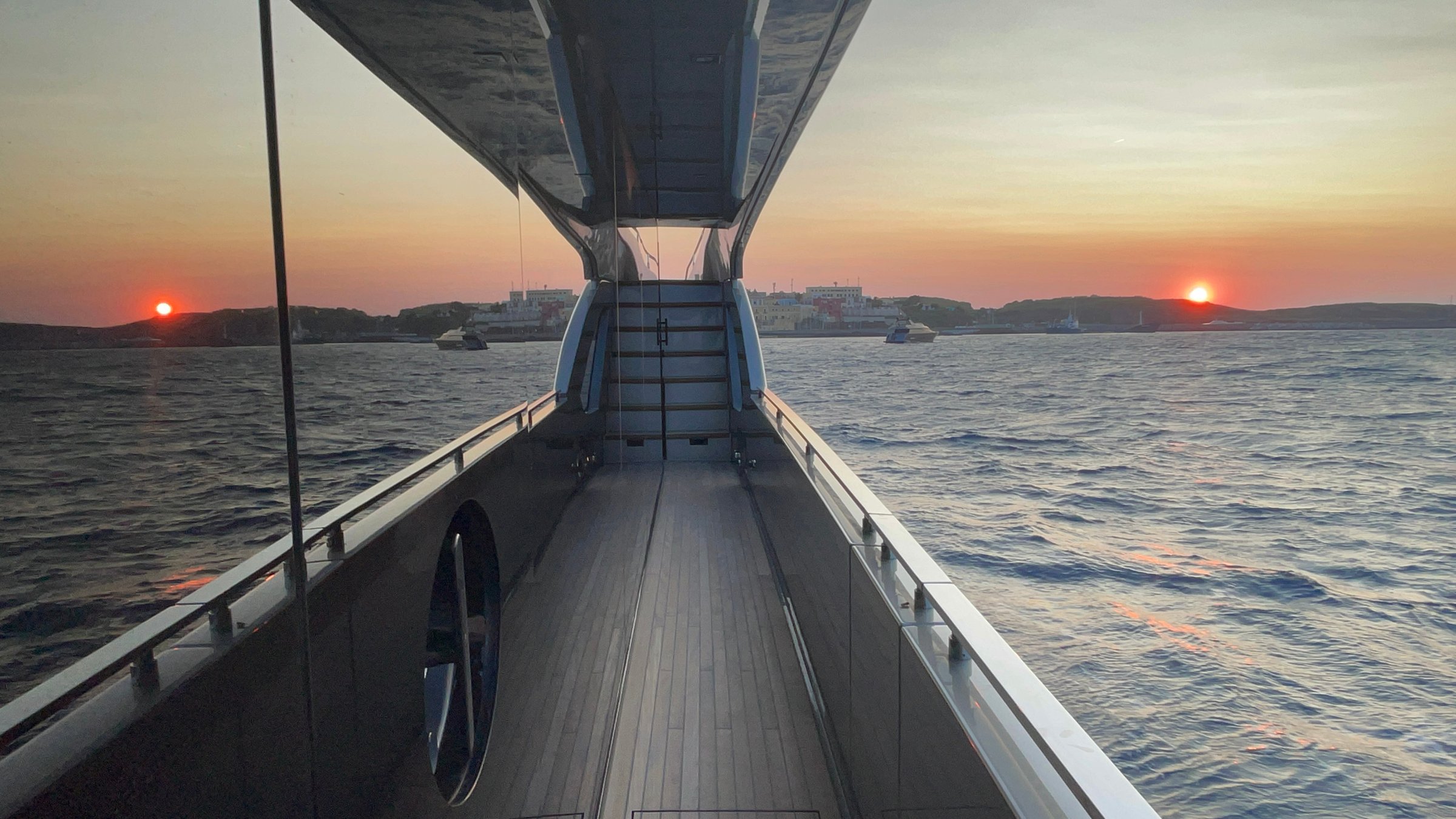 Burnt orange sunset reflecting off the side of a yacht window off the island of Ventotene, Italy.