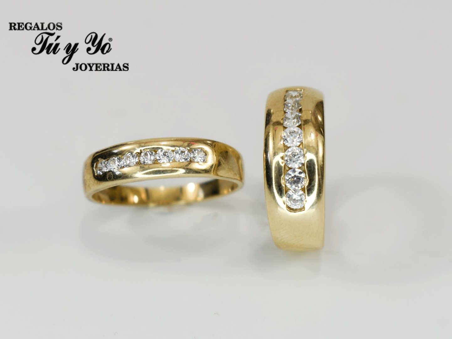 Two gold rings with embedded diamonds displayed on a white surface, with "Regalos Tú y Yo Joyerias" text in the corner.