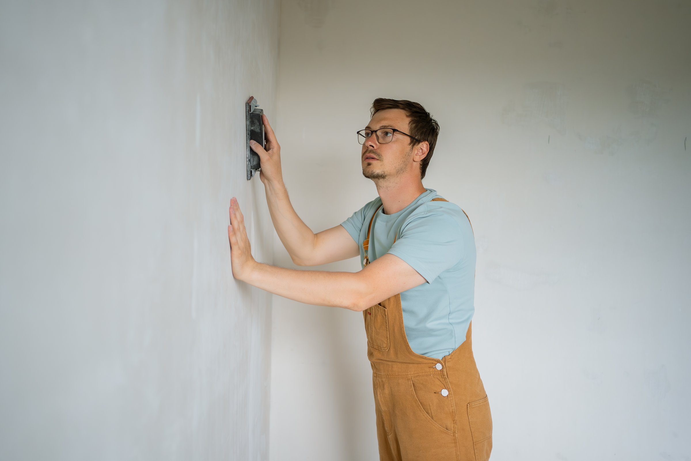Dedicated construction worker expertly smooths a wall using a hand tool. Focused on achieving a perfect finish, he demonstrates precision and attention to detail in his craft