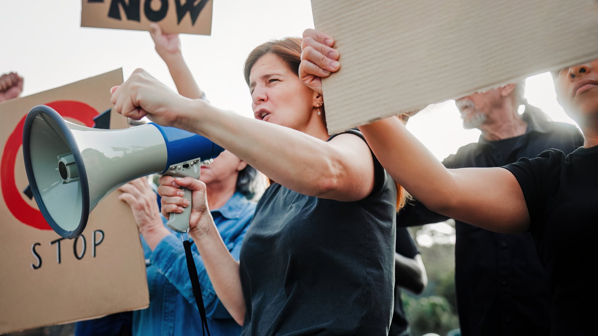Multicultural urban protest for immigrant rights, fists raised, diverse group holding signs in city