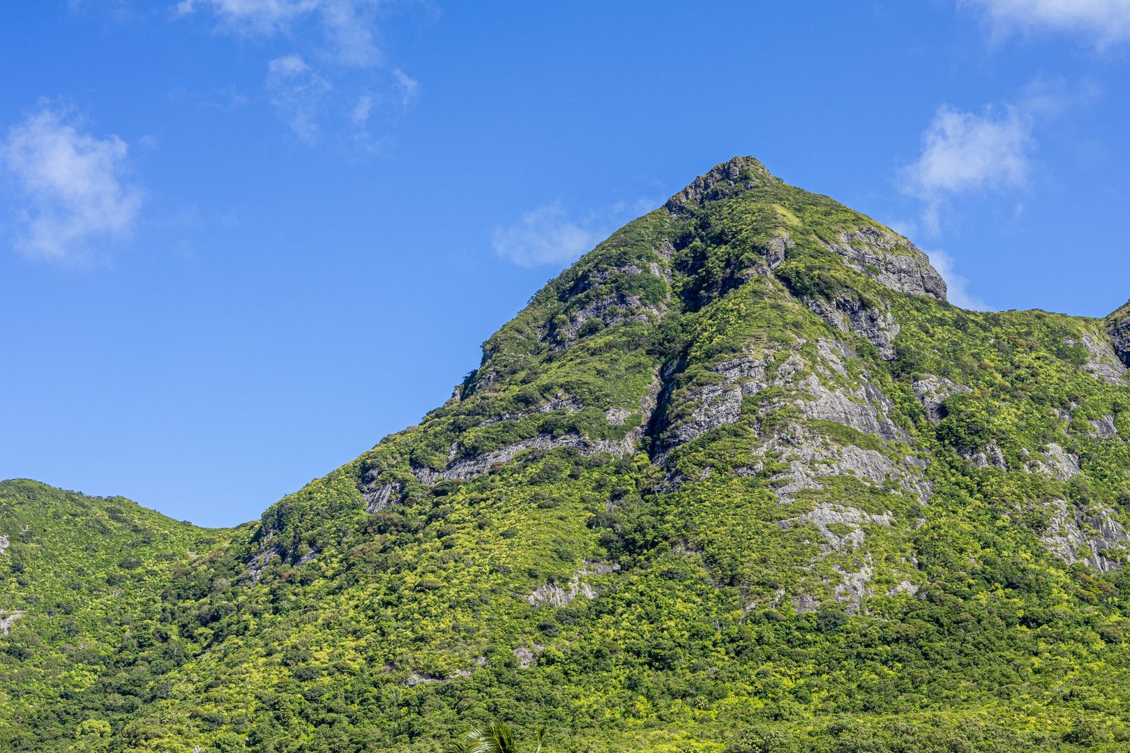 Green mountain peak against blue sky