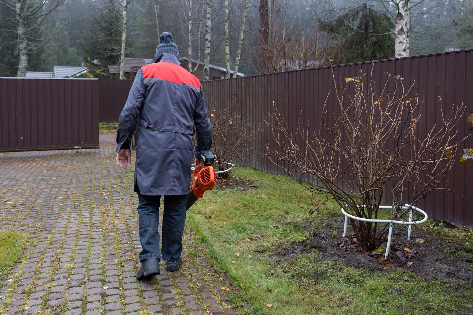 Worker removing fallen leaves with electric blower
