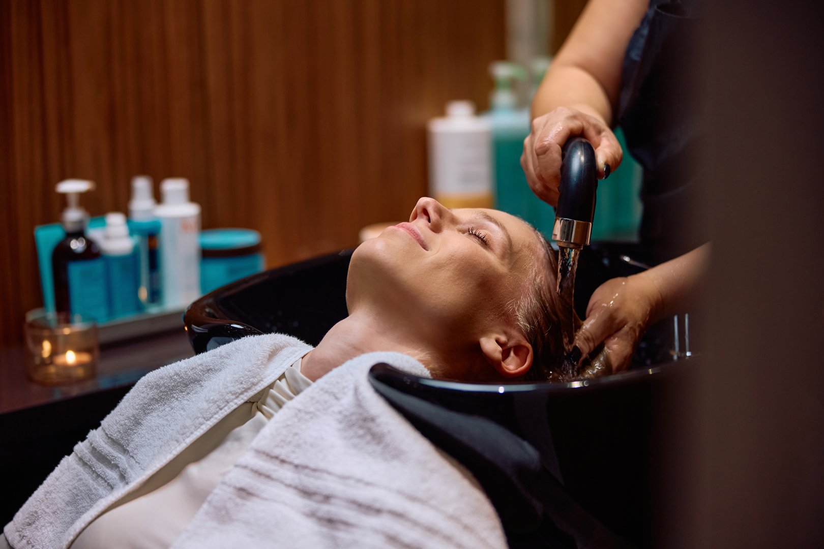 Young woman with eyes closed getting her hair washed at the salon. Copy space.
