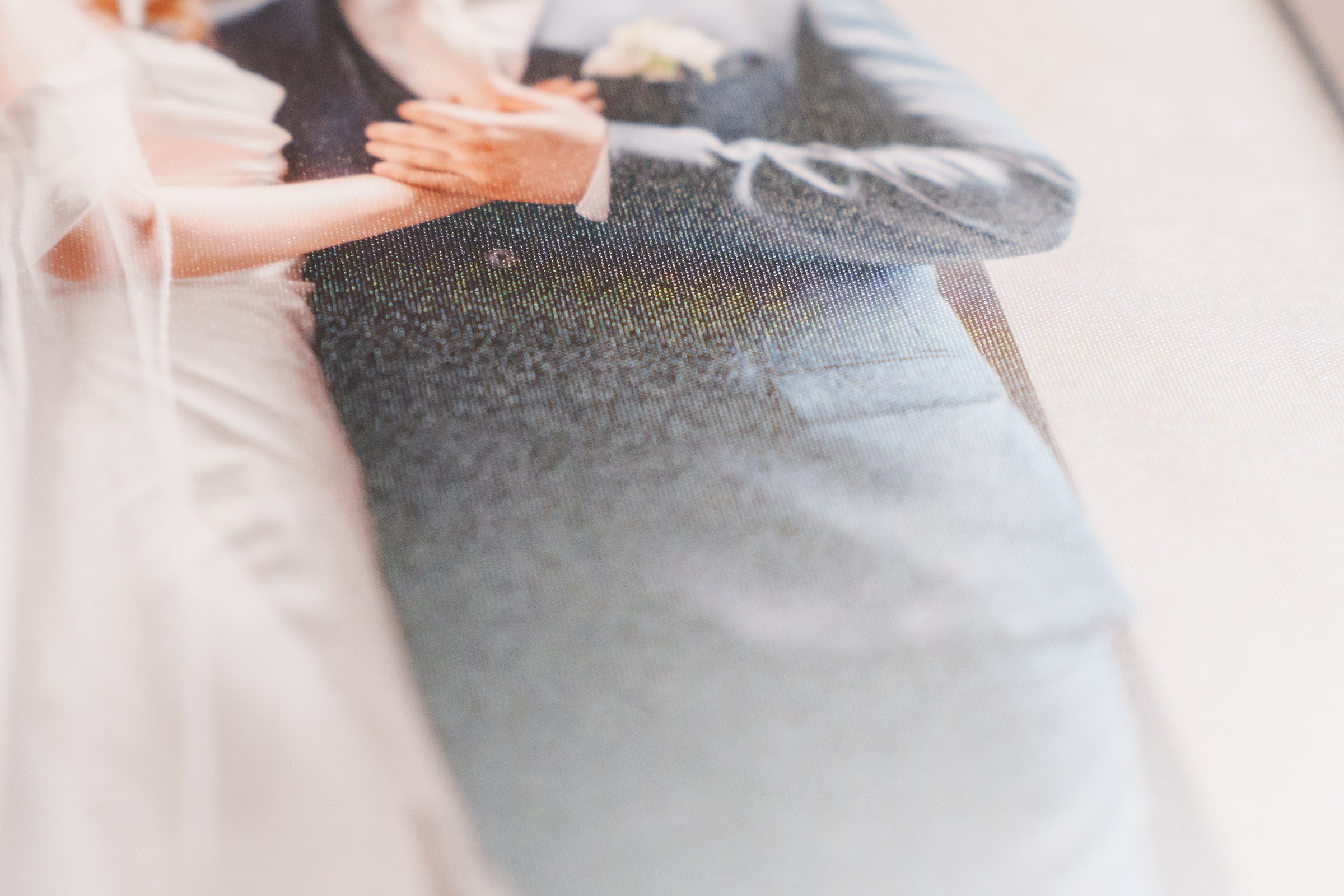 A beautiful wedding album features a close-up of a couple's hands, emphasizing their connection. The soft focus and matte paper create an intimate atmosphere, capturing a special moment.