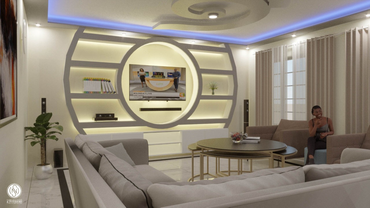 Modern living room with circular wall design, flat-screen TV, sectional sofa, round coffee table, and a person seated.