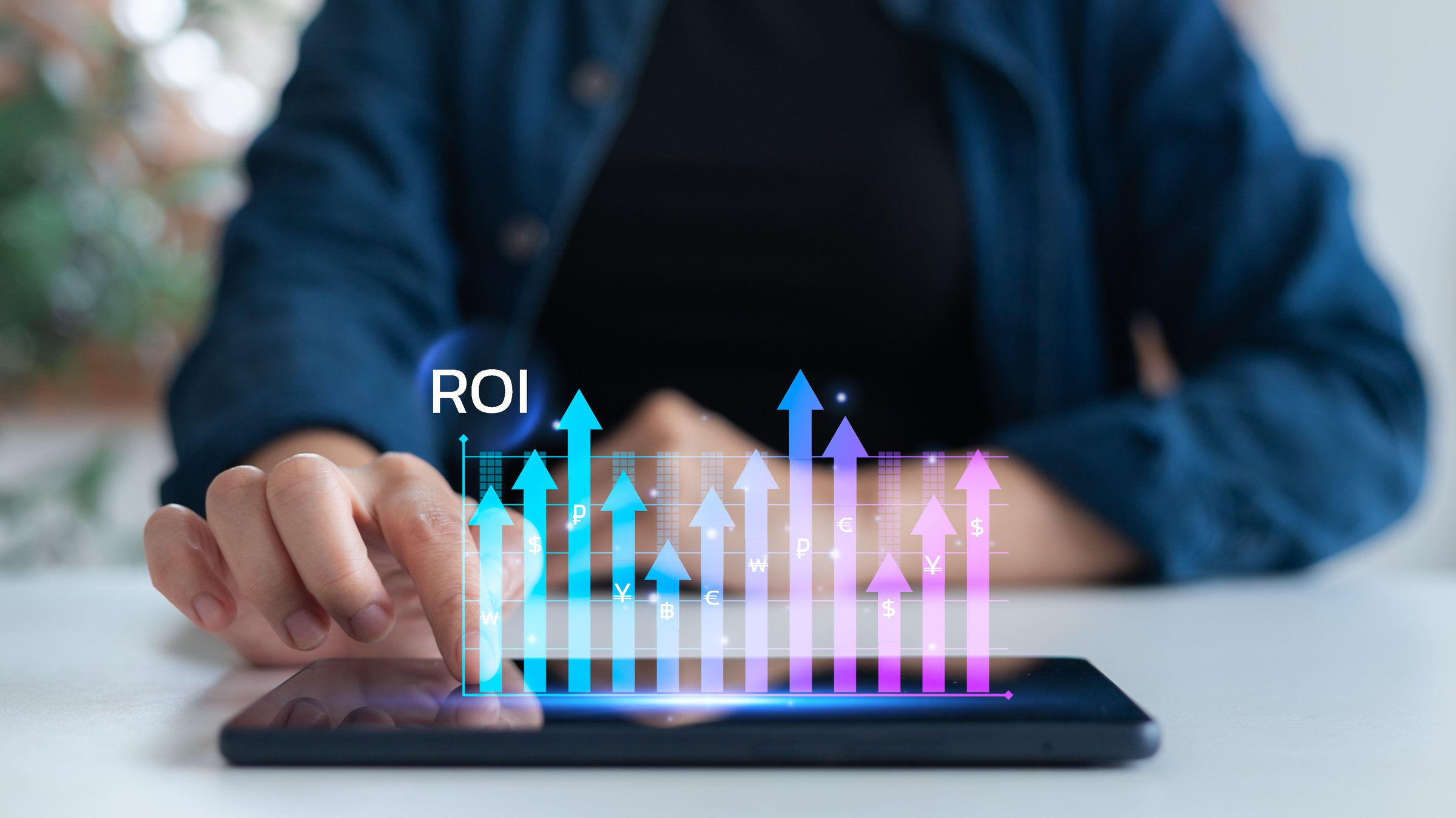 Hand touching tablet screen with ROI and uptrend graph. Concept of return on investment, digital marketing performance, and financial analytics in business strategy.