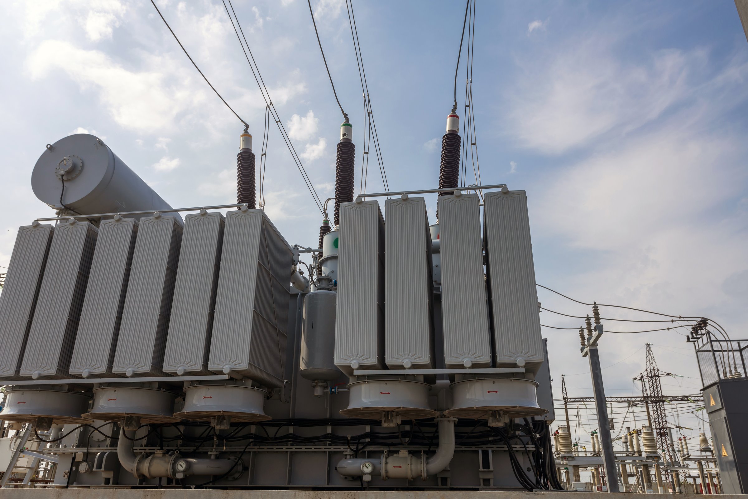 High voltage transformer against a blue sky background. Electric current redistribution substation