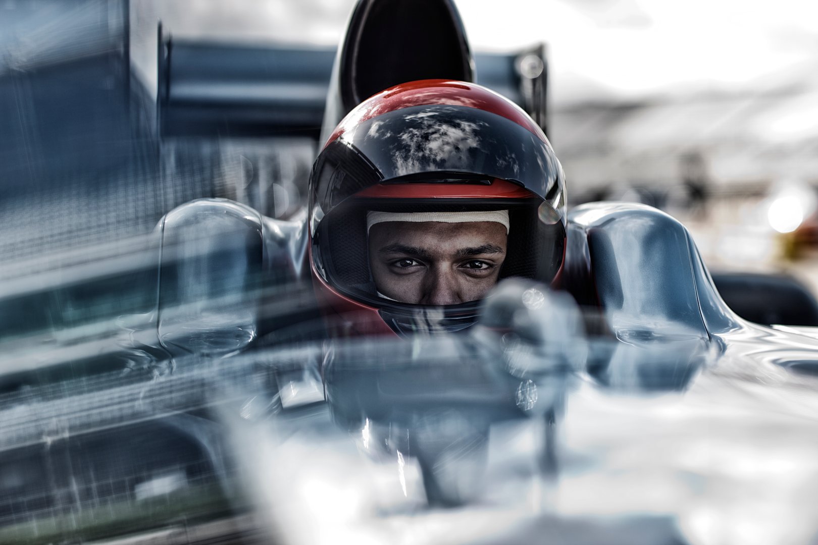 Close-up of a race car driver wearing a helmet, sitting in a sleek, modern race car cockpit. Focus on eyes and helmet.