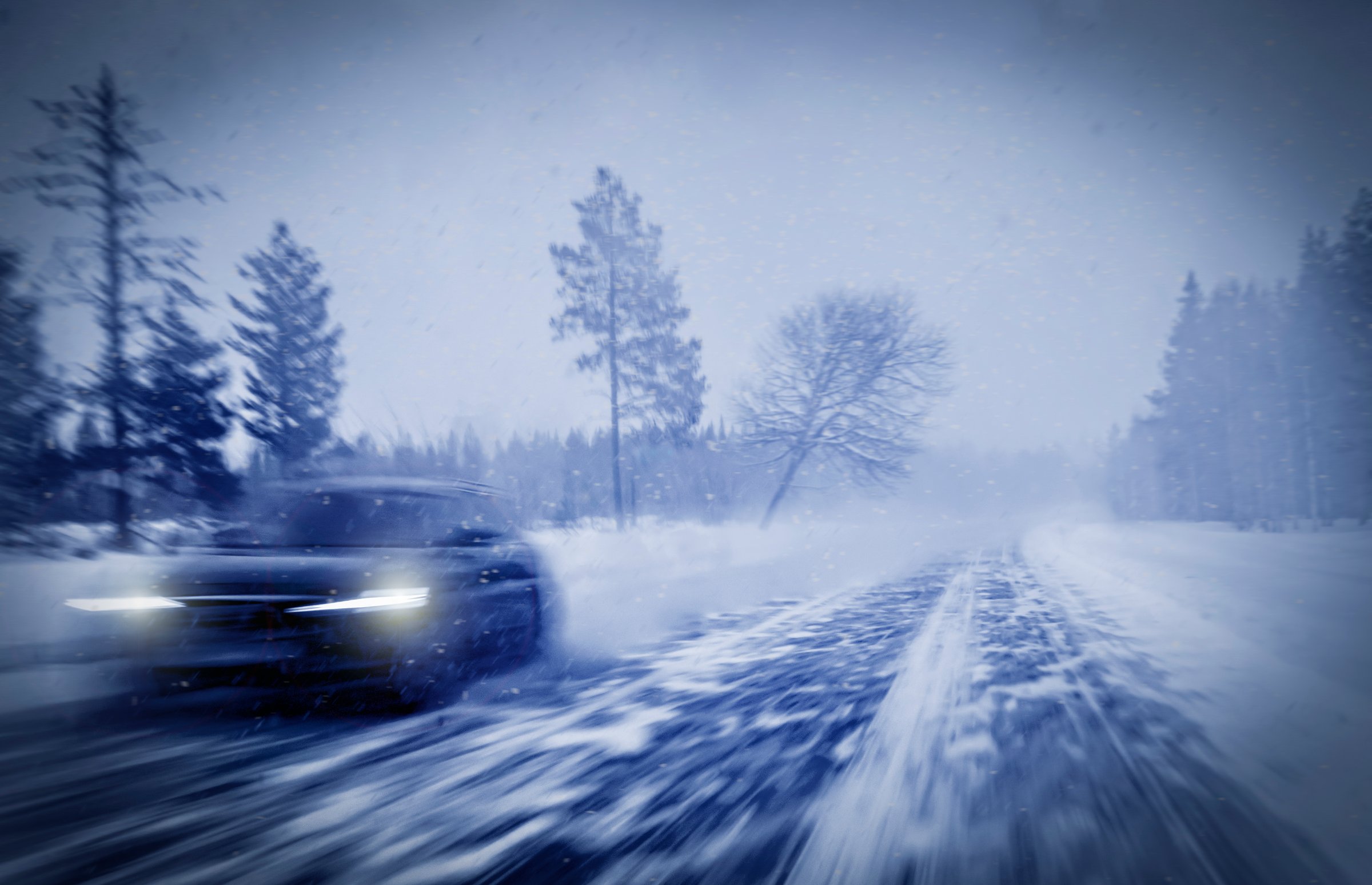 Snow removal services Anchorage Alaska - car driving through heavy snow on winter road demonstrating need for professional 24/7 emergency snow plowing