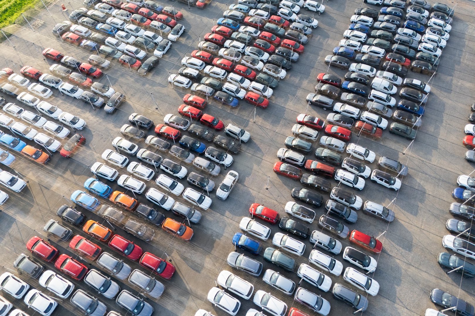 Aerial view of a storage facility for new cars. A lot of cars on the parking. Drone point of view.