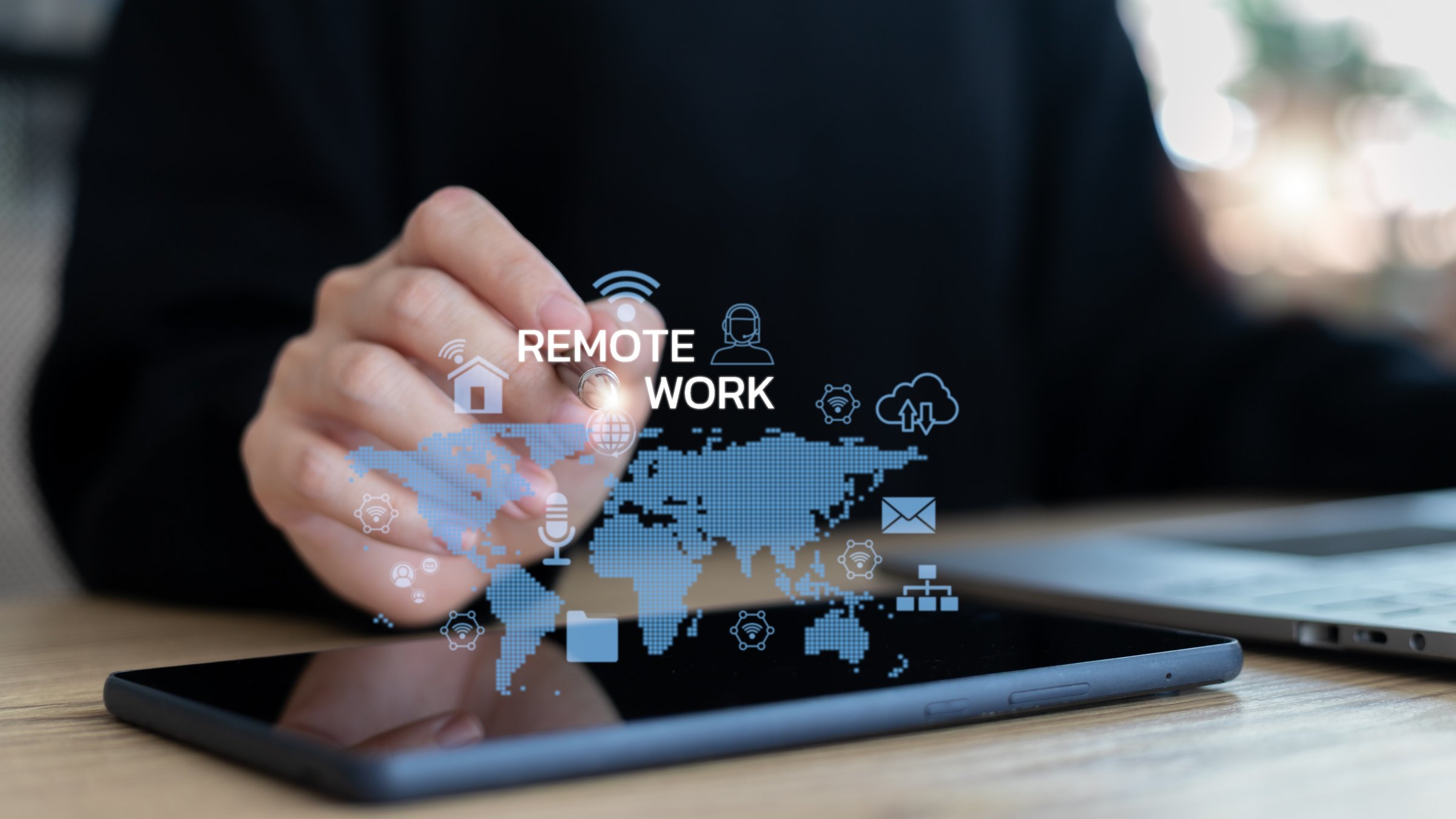 Hand touching digital screen with remote work icons and world map, representing global online communication, remote job, cloud computing, and virtual business connection.