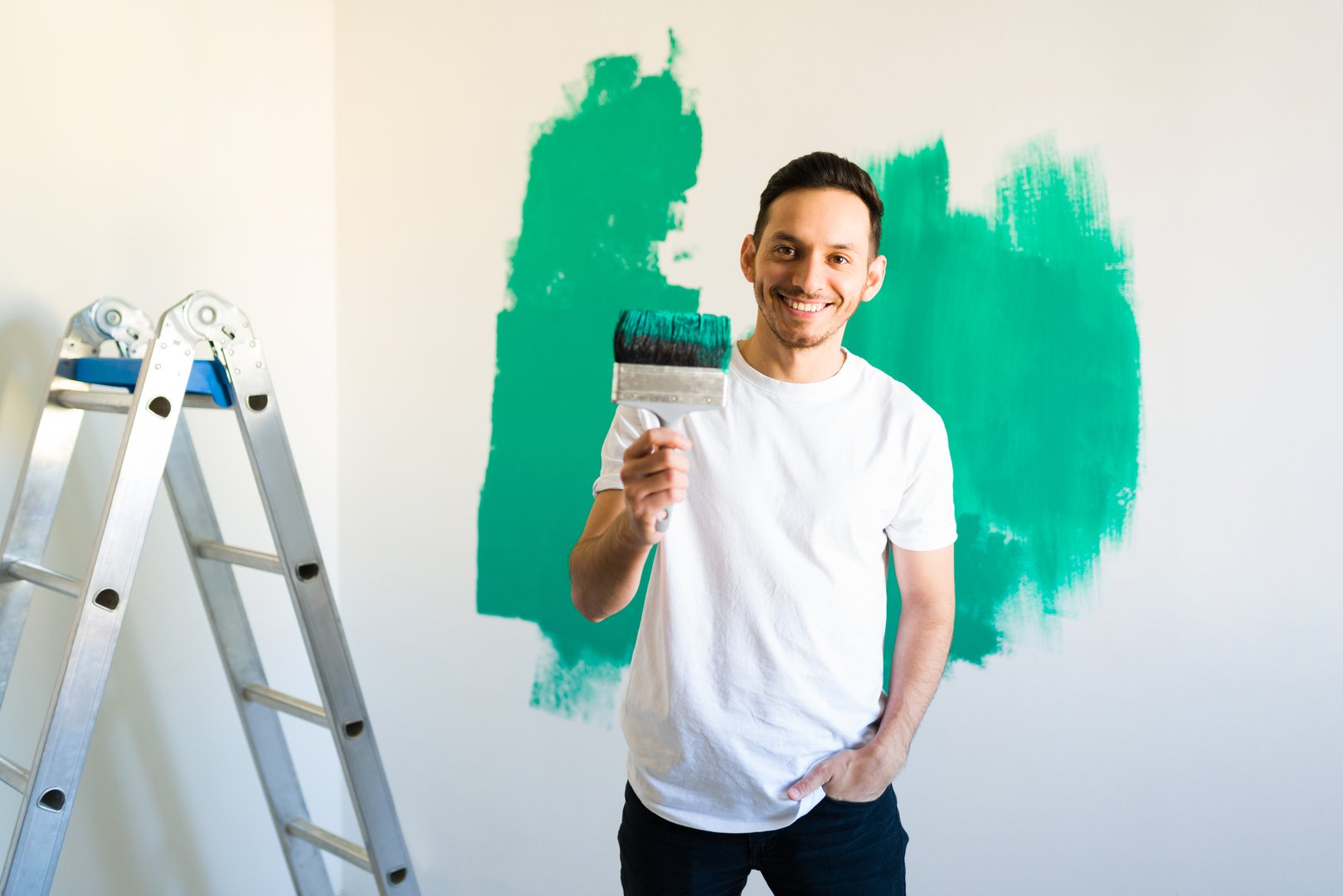 Good-looking man in his 30s smiling while holding a paint roller
