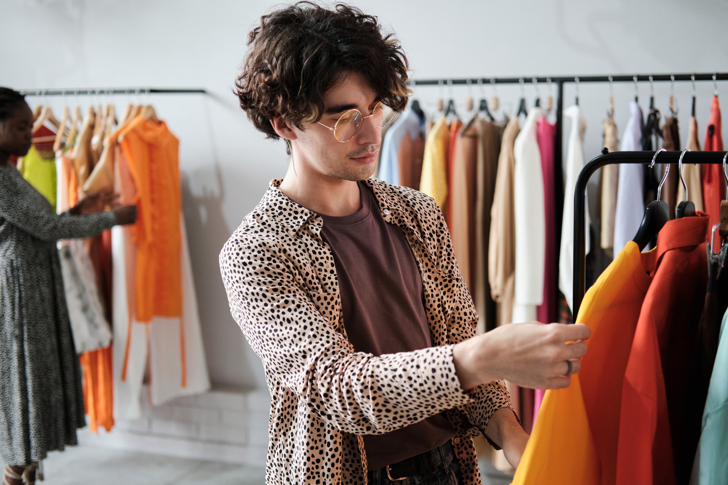 Young stylish man choosing new clothes on the rack and making purchases in the shopping mall
