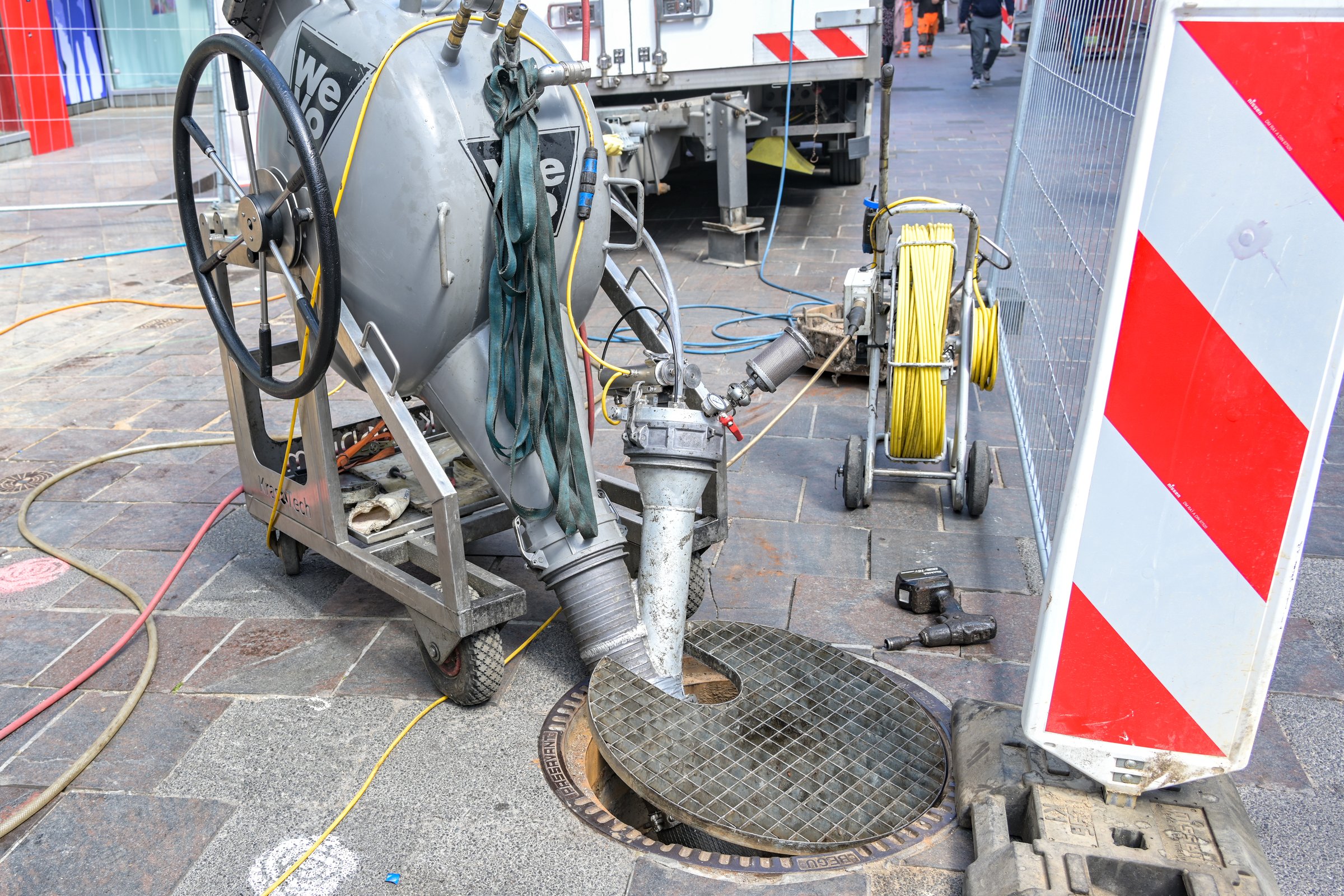 Lubeck, Germany, May 4, 2022: Sewer works with a pumping machine and big hoses at a manhole in a city street, professional technology on a construction site, selected focus