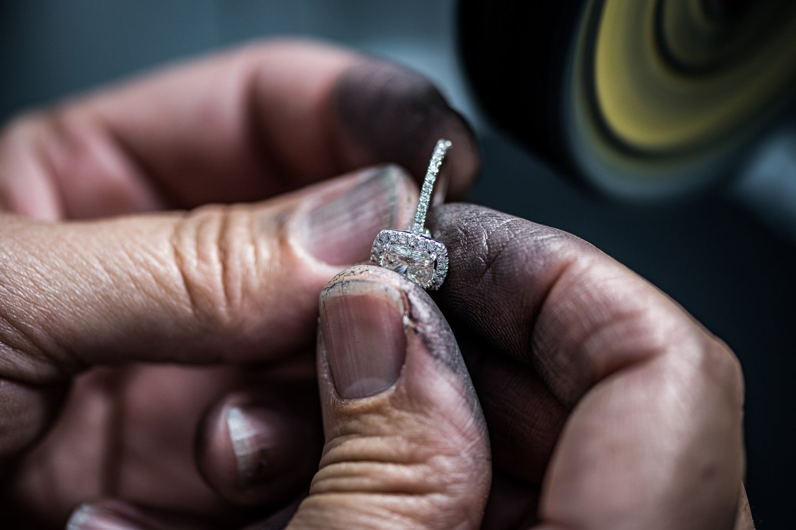 The picture captures the intricate process of handcrafting a jewel, showcasing the skilled artisan's dexterity and precision. The hand is delicately holding a small tool, carefully carving and shaping a piece of precious metal into a beautiful jewel.

The scene is illuminated by bright studio lighting, highlighting the details and texture of the metal. The tool and the metal shavings surrounding the hand add a sense of authenticity and craftsmanship to the image.

The hand itself is graceful and poised, showing the concentration and dedication of the artisan. The jewelry in progress is partially visible, allowing the viewer to imagine the final product and the amount of work that goes into creating such a piece.

Overall, the image conveys a sense of artistry and beauty, highlighting the timeless craft of handmade jewelry and the importance of skilled artisans in creating unique and precious items.